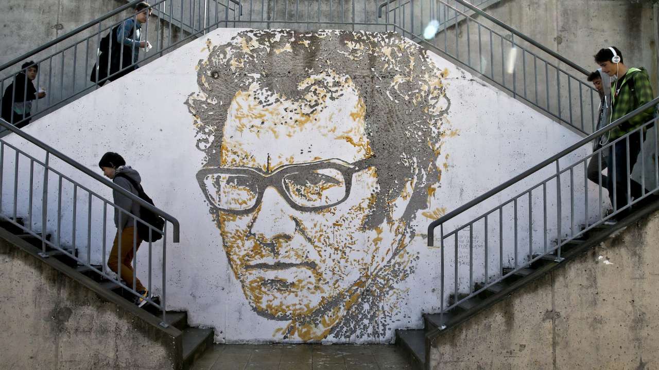 Alunos da escola secundária José Afonso passam junto a uma criação do artiista português Alexandre Farto, que assina Vhils, do cantor Zeca Afonso