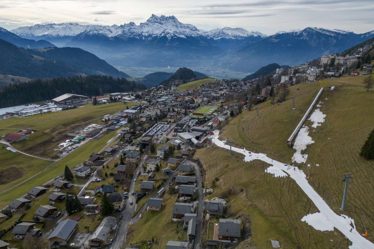 Skiers pass on a small layer of artificial snow amid warmer-than-usual winter temperatures in the Alps in Leysin, Switzerland, January 4, 2023. REUTERS/Denis Balibouse TPX IMAGES OF THE DAY