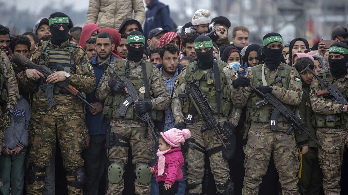 epaselect epa11915720 A Palestinian girl stands near armed fighters from Hamas' Izz ad-Din al-Qassam Brigades during the handover of three Israeli hostages to Red Cross representatives in Al Nuseirat refugee camp, central Gaza Strip, 22 February 2025. Six Israeli hostages were released on 22 February -- three in Nuseirat, two in Rafah and one in Gaza City -- after Hamas handed them over to the Red Cross in Gaza as part of the first phase of the Israel-Hamas ceasefire deal.  EPA/MOHAMMED SABER