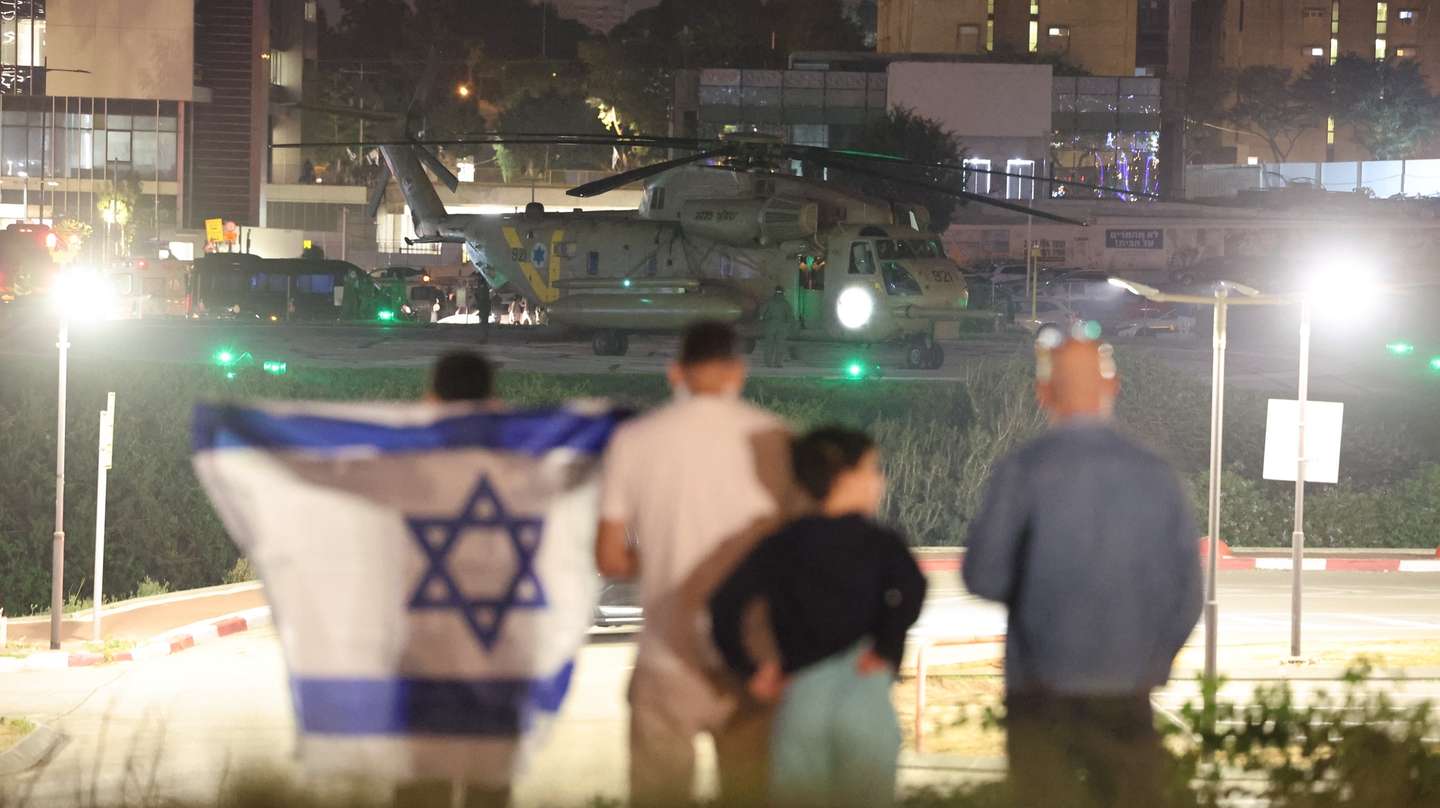 epa10993393 People with an Israeli flag looks on as an Israeli army helicopter carrying Israeli children hostages who were held by Hamas in Gaza, landed at the helipad of the Schneider-Children's Medical Center in Petah Tikva, Israel, 24 November 2023. Israel and Hamas agreed to a four-day ceasefire agreement, mediated by Qatar, the US, and Egypt, that came into effect at 05:00 AM GMT on 24 November, with 50 Israeli hostages, women and children, to be released by Hamas and 150 Palestinian women and children that were detained in Israeli prisons to be released in exchange. More than 14,000 Palestinians and at least 1,200 Israelis have been killed, according to the Gaza Government media office and the Israel Defense Forces (IDF), since Hamas militants launched an attack against Israel from the Gaza Strip on 07 October, and the Israeli operations in Gaza and the West Bank which followed it.  EPA/ABIR SULTAN