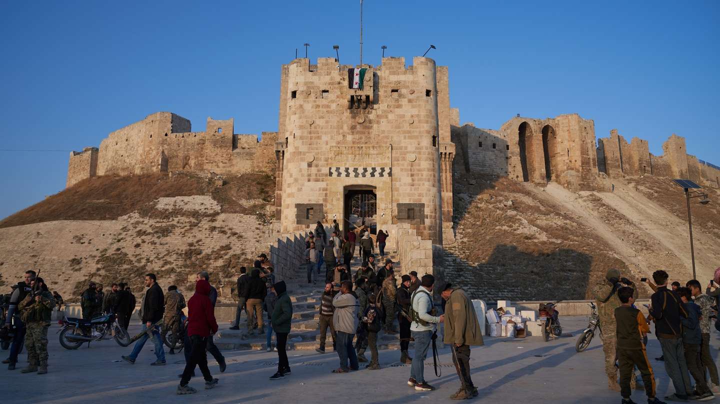 epa11750347 Syrian opposition fighters gather near Aleppo's Historic Citadel in central Aleppo, Syria, 30 November 2024. Syrian opposition forces have taken significant control of Aleppo, a major city and former economic hub of Syria, after intense battles with government forces. The offensive triggered Russian strikes on Aleppo 30 November 2024, the first since 2016, and saw Syria's military withdraw its troops from the city. The attack was led by the Islamist militant group Hayat Tahrir al-Sham (HTS).  EPA/KARAM AL-MASRI