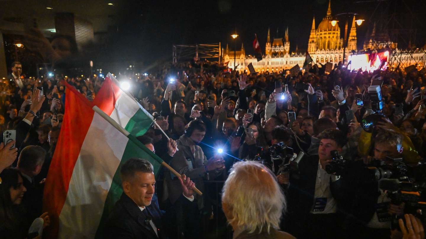 epa12886131 Chairman of the Tisza Party Peter Magyar (L) holds a national flag during the party's election night watch event, after the party won a landslide victory in the general elections in Budapest, Hungary, 12 April 2026.  EPA/Tibor Illyes HUNGARY OUT