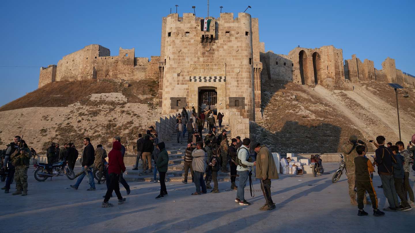 epa11750347 Syrian opposition fighters gather near Aleppo's Historic Citadel in central Aleppo, Syria, 30 November 2024. Syrian opposition forces have taken significant control of Aleppo, a major city and former economic hub of Syria, after intense battles with government forces. The offensive triggered Russian strikes on Aleppo 30 November 2024, the first since 2016, and saw Syria's military withdraw its troops from the city. The attack was led by the Islamist militant group Hayat Tahrir al-Sham (HTS).  EPA/KARAM AL-MASRI