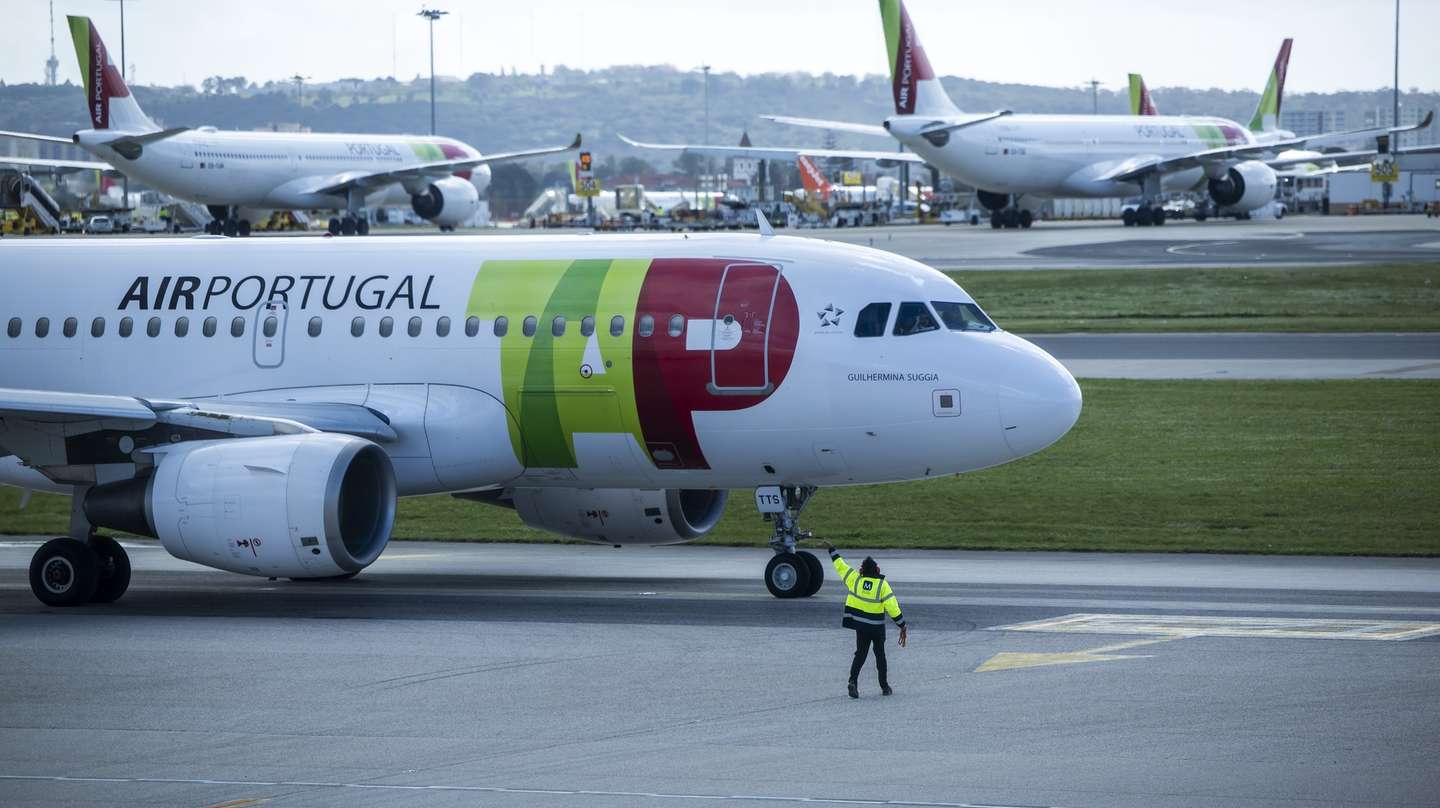 Um trabalhador de placa dá indicações a um piloto num avião da TAP, no Aeroporto Humberto Delgado, em Lisboa, 15 de abril de 2025.  JOSÉ SENA GOULÃO/LUSA
