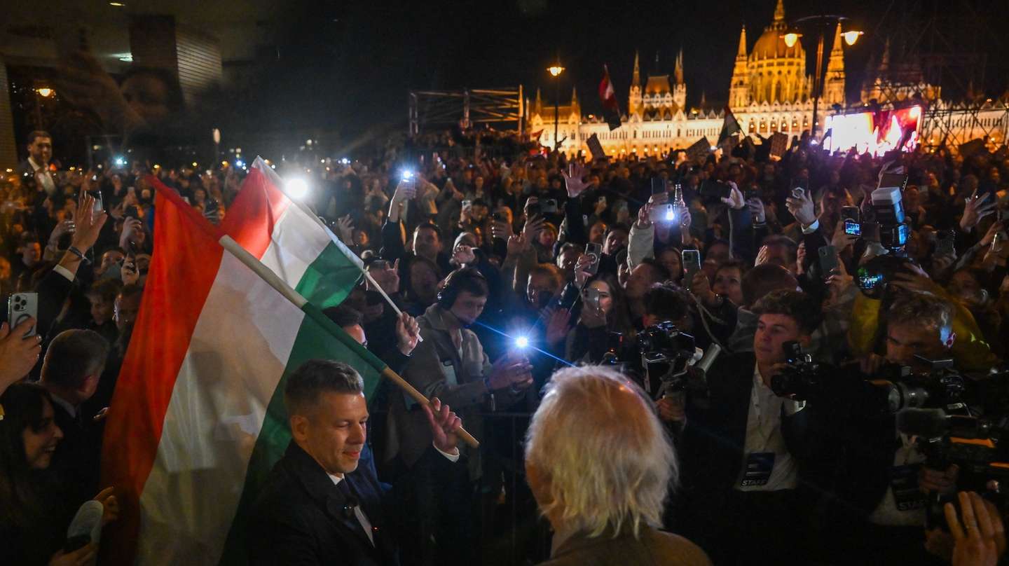 epa12886131 Chairman of the Tisza Party Peter Magyar (L) holds a national flag during the party's election night watch event, after the party won a landslide victory in the general elections in Budapest, Hungary, 12 April 2026.  EPA/Tibor Illyes HUNGARY OUT
