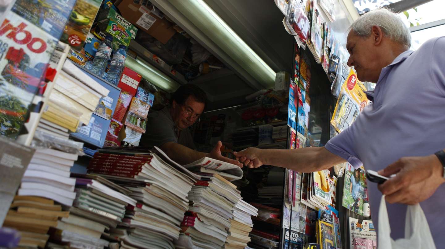 Um popular compra os jornais num quiosque de venda de revistas e jornais, em Lisboa, 13 de julho de 2013. Nos últimos anos, na Avenida da Liberdade, em miradouros pelas sete colinas, nos jardins, à beira Tejo, nas praças, os quiosques foram nascendo ou ganhando vida “como cogumelos” e, reinventando um centenário hábito lisboeta, puseram a cidade a mexer. (ACOMPANHA TEXTO). MIGUEL A. LOPES / LUSA