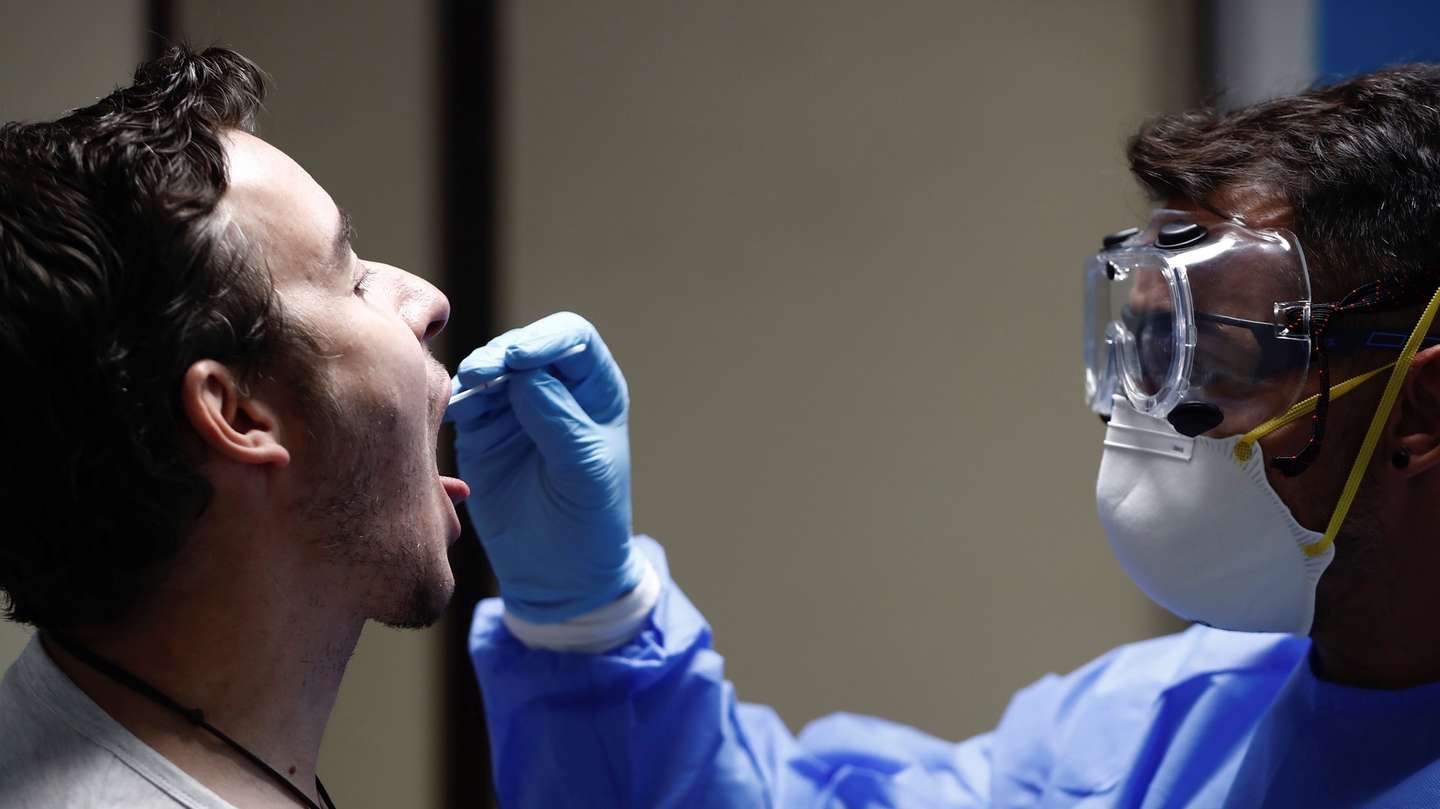 epa08608804 A health worker takes a swab sample from a young man for a PCR covid-19 test in Carabanchel district in Madrid, Spain, 17 August 20202. PCR tests are taking place in Carabanchel to test people between 15 and 49 years old, as the average age of coronavirus patients has considerably gone down in the Spanish capital city.  EPA/Mariscal