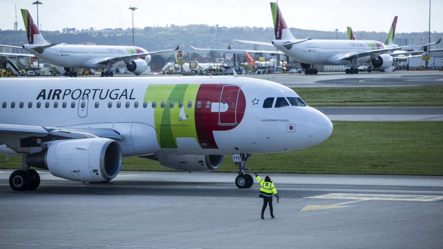 Um trabalhador de placa dá indicações a um piloto num avião da TAP, no Aeroporto Humberto Delgado, em Lisboa, 15 de abril de 2025.  JOSÉ SENA GOULÃO/LUSA