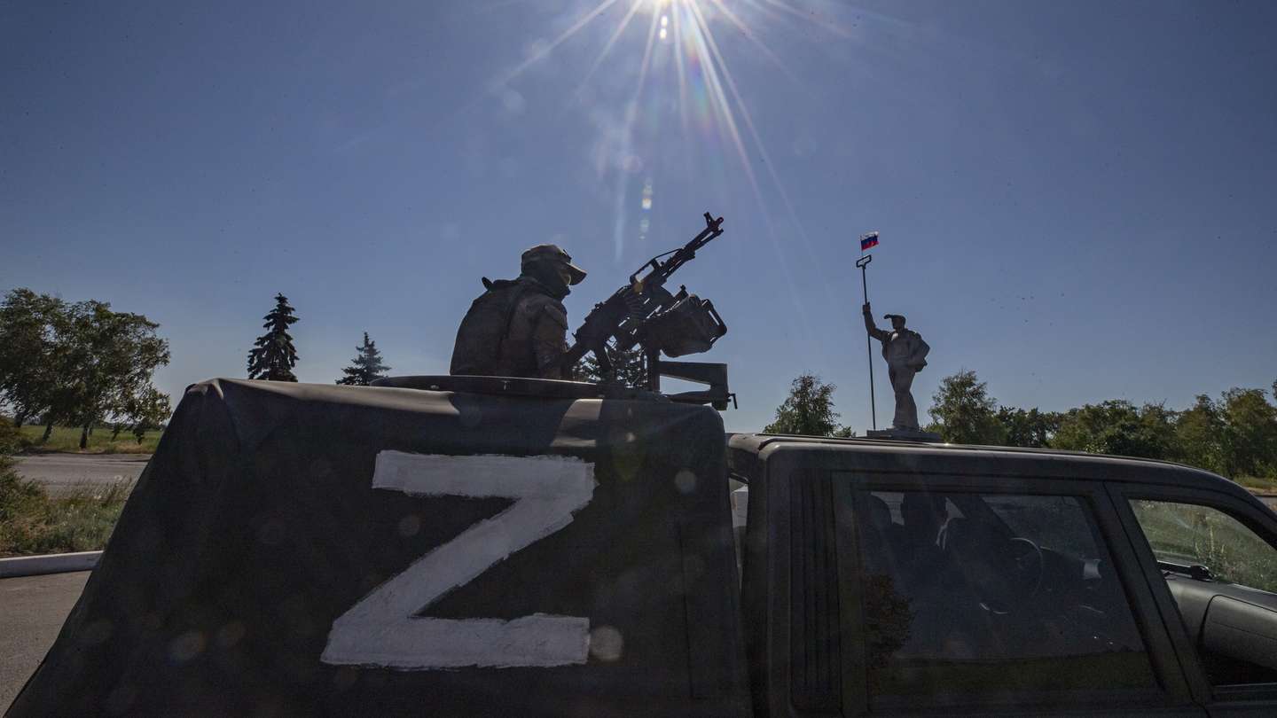 epa10009665 A picture taken during a visit to Mariupol organized by the Russian military shows a Russian serviceman in a vehicle with letter 'z' guards on the road in front of the monument of steel worker with Russian National flag at the entrance to the city of Mariupol, Donetsk region, Ukraine, 12 June 2022. On 24 February Russian troops entered Ukrainian territory starting a conflict that has provoked destruction and a humanitarian crisis. According to the UNHCR, more than six million refugees have fled Ukraine, and a further 7.7 million people have been displaced internally within Ukraine since.  EPA/SERGEI ILNITSKY