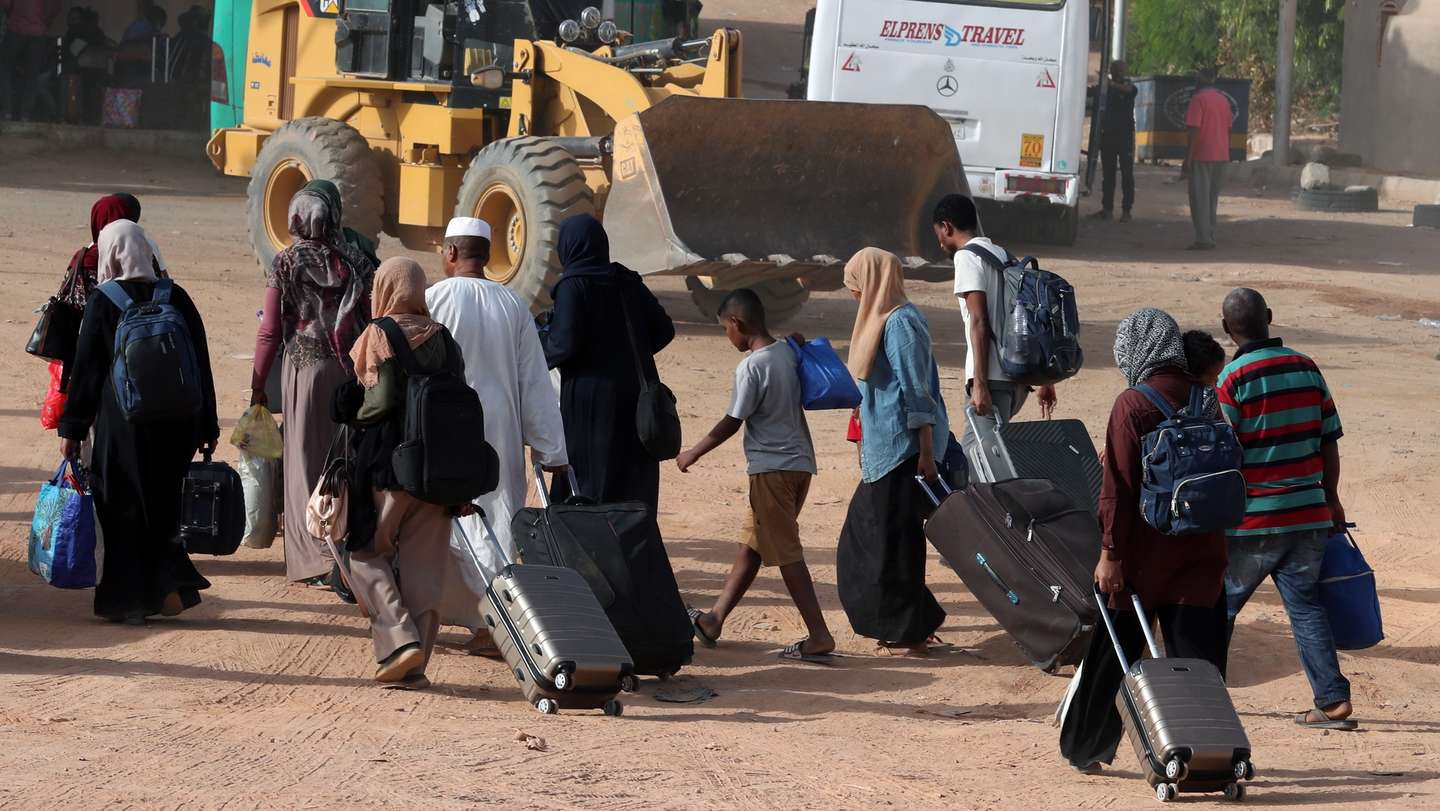 epa10635710 Sudanese people walk with belongings after crossing the border from Sudan, Abu Simbel, southern Egypt, 18 May 2023.  According to the UNHCR office, 83,758 Sudanese have crossed into Egypt since the beginning of an armed conflict on 15 April between the Sudanese military and the RSF (Rapid Support Forces) militia. The UN estimates some 200,000 people have fled Sudan since the conflict erupted  EPA/KHALED ELFIQI