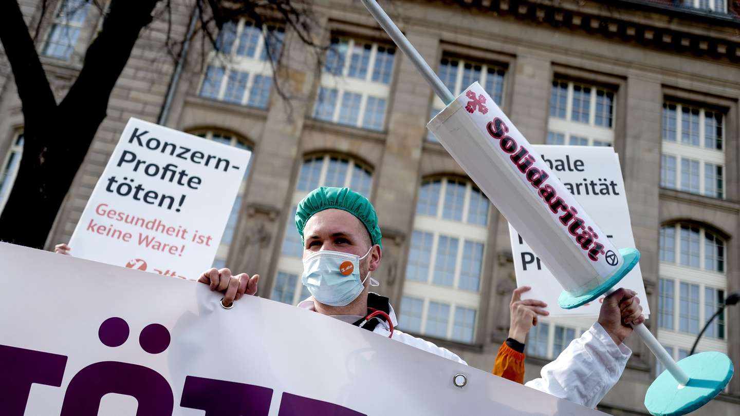 epa09065297 Activist holds a giant Syringe with sign "Solidarity" during a protest ´Vaccines belong to everyone!´ in front of the Economy ministry in Berlin, Germany, March 10, 2021, Activists call for the coronavirus  (COVID-19) vaccines patents that they may be produced all over the world  EPA/FILIP SINGER