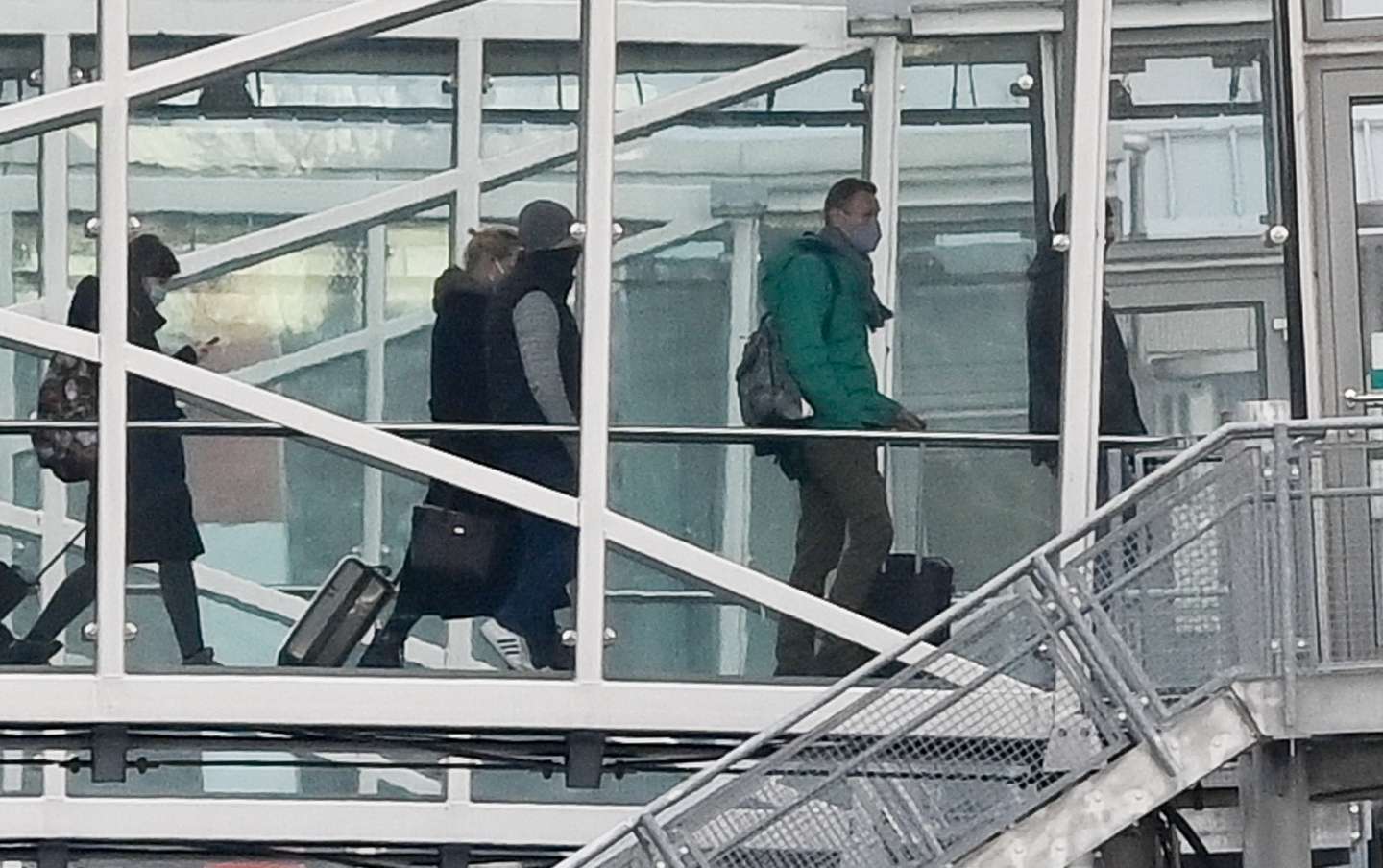 epaselect epa08943757 Russian opposition leader Alexei Navalny (2nd-R) enters a Pobeda airlines plane through tunnel, in which Russian opposition leader Alexei Navalny and his wife Yulia Navalnaya are to fly to Moscow, arrives at the Berlin Brandenburg International Airport BER in Schoenefeld, Germany, 17 January 2021. Navalny plans to return to Russia on a scheduled flight to Moscow later in the afternoon on 17 January. He was treated at the Charite hospital in Berlin since 22 August 2020 for being poisoned with a nerve agent from the Novichok group and was discharged from acute inpatient care on 22 September 2020.  EPA/FILIP SINGER