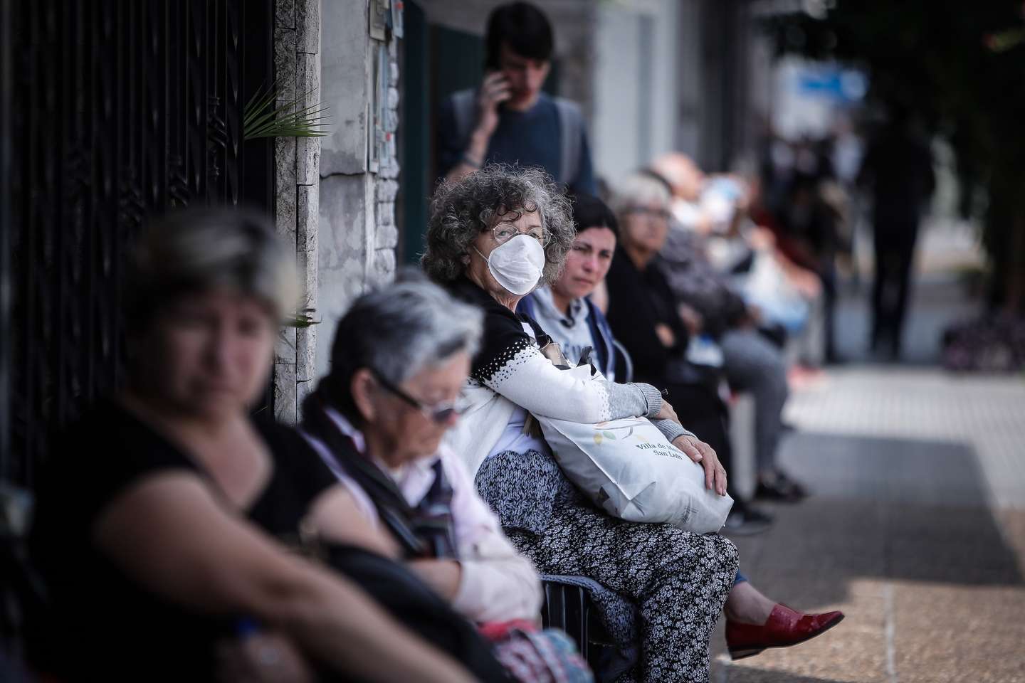 epa08342104 Pensioners sit waiting to enter their bank to collect their pension payments in Buenos Aires, Argentina, 03 April 2020. The mostly-elderly people lining up at banks around the country braved the restrictions of the national lockdown imposed by the government in a bid to spread of the pandemic COVID-19 disease caused by the SARS-CoV-2 coronavirus in order to retreive their pensions at the start of a month filled with global economic uncertainty.  EPA/JUAN IGNACIO RONCORONI