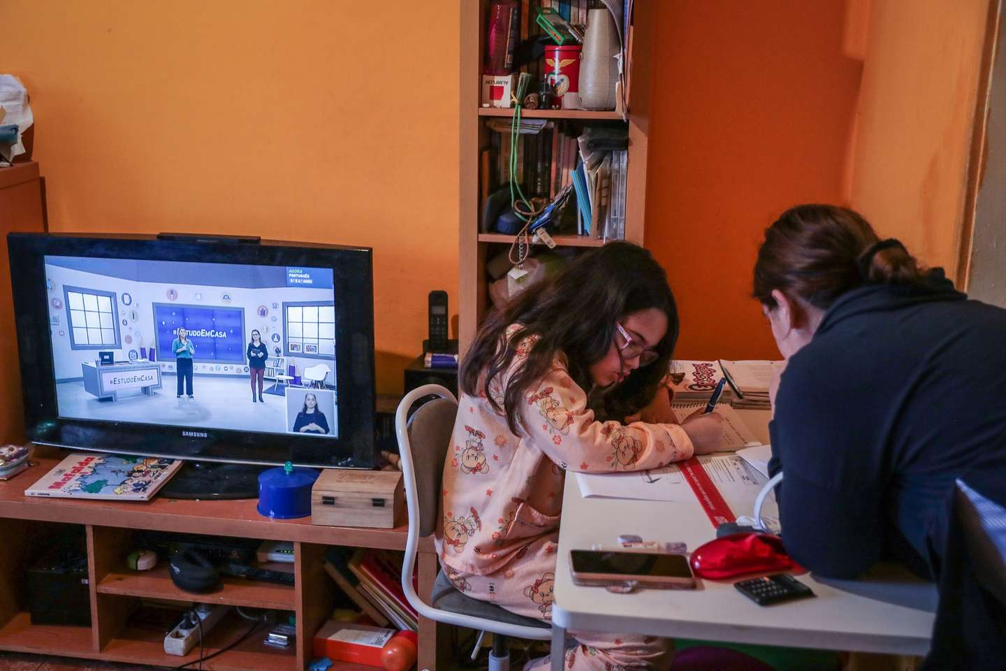 Daniela de 09 anos é auxiliada pela sua mãe, Ana Costa, enquanto assiste às aulas pela televisão, na Amadora, 20 de abril de 2020. Mais de 850 mil alunos do ensino básico contam a partir de hoje e durante o terceiro período, entre as 9:00 e as 17:30, mais de uma centena de professores vão dar aulas de apoio através da televisão, e vão aprender com a ajuda de mais de uma centena professores à distância devido à pandemia de covid-19. O Governo decretou o estado de emergência a 19 de março, que já foi prorrogado duas vezes, estando previsto agora o seu fim a 02 de maio. TIAGO PETINGA/LUSA