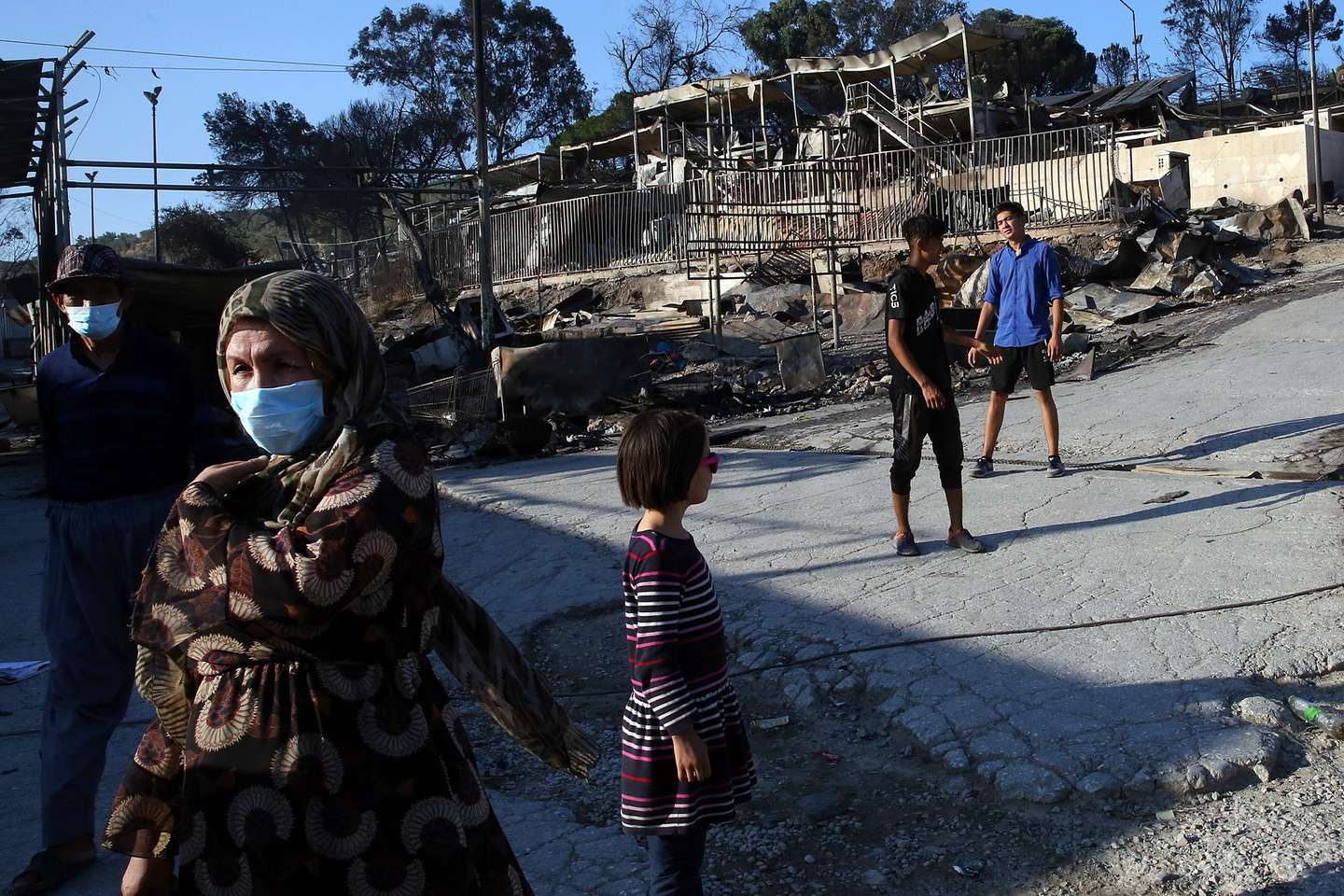 epa08657004 Asylum seekers among debris in the Moria refugees camp on the island of Lesbos, Greece, 09 September 2020. According to reports, a fire broke out at Moria Camp early on 09 September, after approximately 35 refugees, who had tested positive for COVID-19, refused to move into isolation with their families.  EPA/ORESTIS PANAGIOTOU