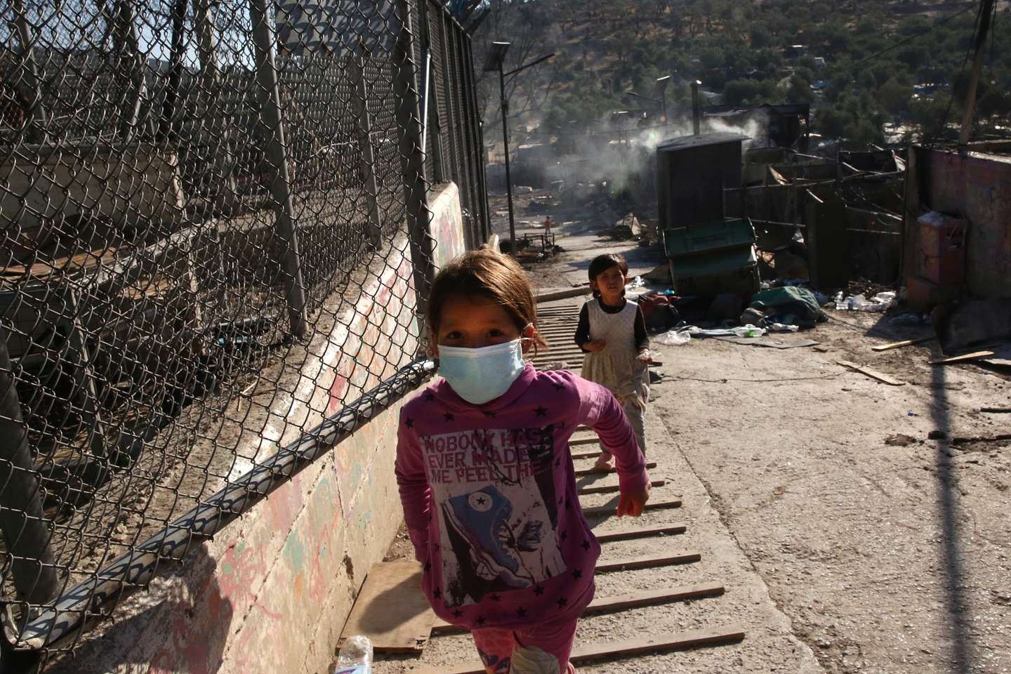 epa08656983 Asylum seekers walk among debris in the Moria refugees camp on the island of Lesbos, Greece, 09 September 2020. According to reports, a fire broke out at Moria Camp early on 09 September, after approximately 35 refugees, who had tested positive for COVID-19, refused to move into isolation with their families.  EPA/ORESTIS PANAGIOTOU