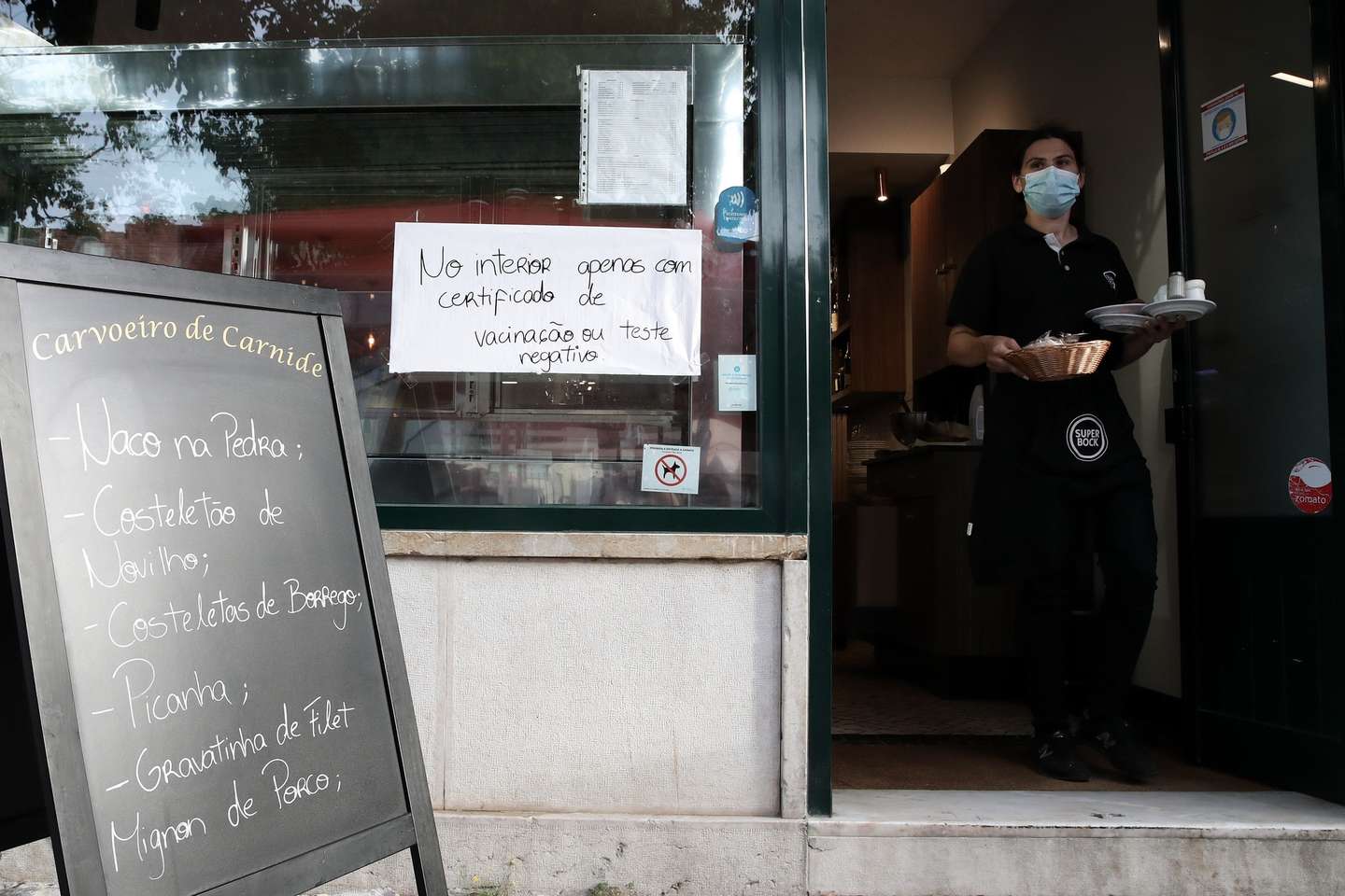 Aviso sobre certificado digital ou teste à entrada de um restaurante em Lisboa, após o Governo decreta que os restaurantes em concelhos de risco elevado ou muito elevado – um total de 60 – passam a ter de exigir certificado digital ou teste negativo à covid-19 a partir das 19:00 de sexta-feira e aos fins de semana para refeições no interior, Lisboa, 10 de julho de 2021. As pessoas em esplanadas que precisarem de entrar nos restaurantes para acesso aos serviços comuns, como instalações sanitárias, ou para efetuarem pagamento, estão dispensadas de apresentar um teste negativo à covid-19 ou o certificado digital. MANUEL DE ALMEIDA/LUSA