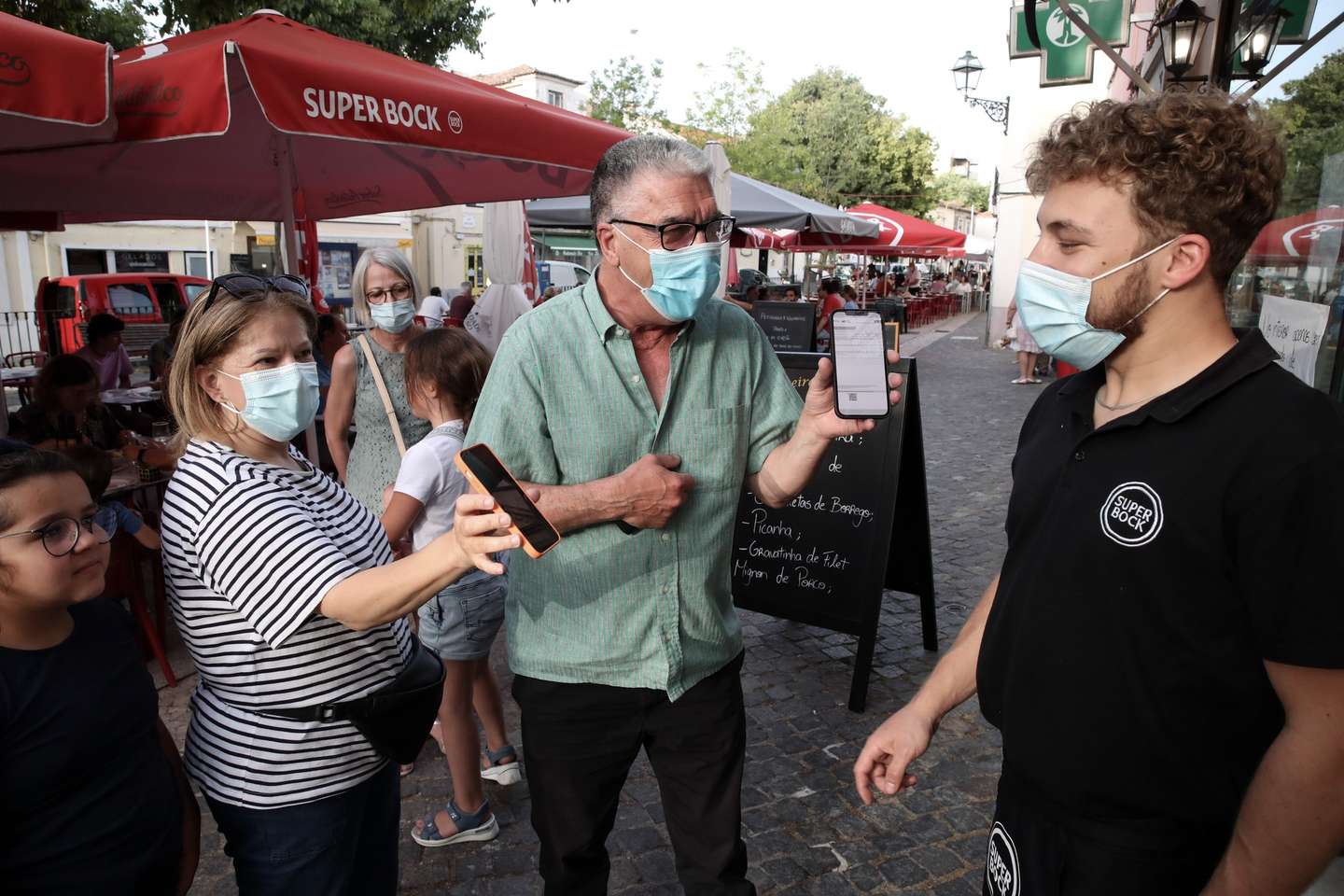 Clientes exibem o certificado digital à entrada de um restaurante em Lisboa, após o Governo decreta que os restaurantes em concelhos de risco elevado ou muito elevado – um total de 60 – passam a ter de exigir certificado digital ou teste negativo à covid-19 a partir das 19:00 de sexta-feira e aos fins de semana para refeições no interior, Lisboa, 10 de julho de 2021. As pessoas em esplanadas que precisarem de entrar nos restaurantes para acesso aos serviços comuns, como instalações sanitárias, ou para efetuarem pagamento, estão dispensadas de apresentar um teste negativo à covid-19 ou o certificado digital. MANUEL DE ALMEIDA/LUSA