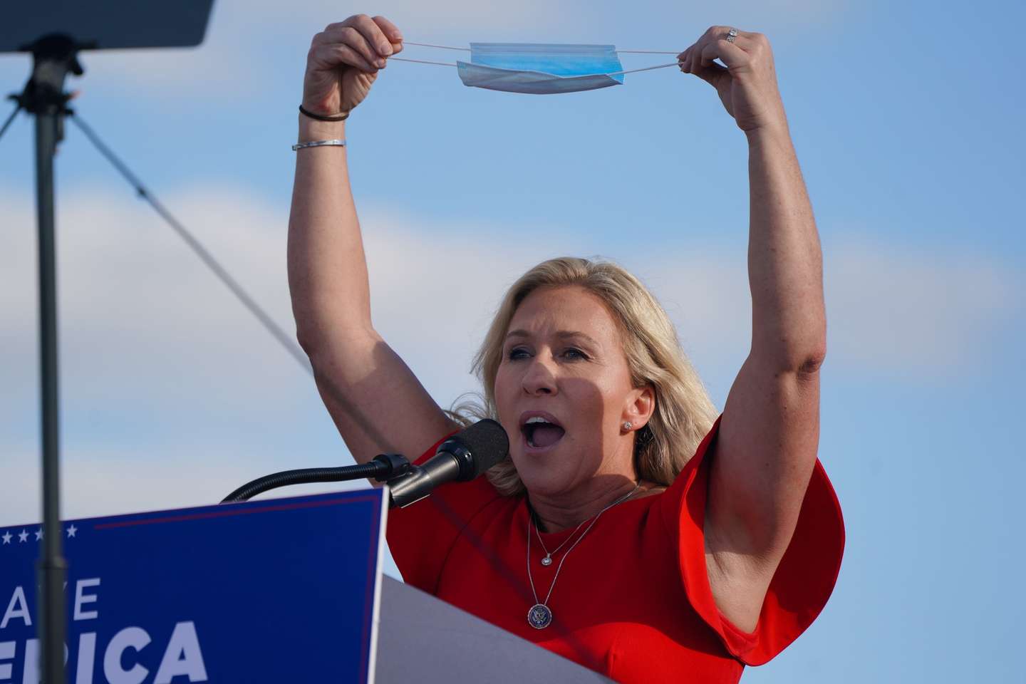 epa09488844 Republican congresswoman Marjorie Taylor Greene holds up a facemask at a Donald Trump rally sponsored by 'Save America' at the Georgia National Fairgrounds in Perry, Georgia, USA, 25 September 2021.  EPA/ELIJAH NOUVELAGE