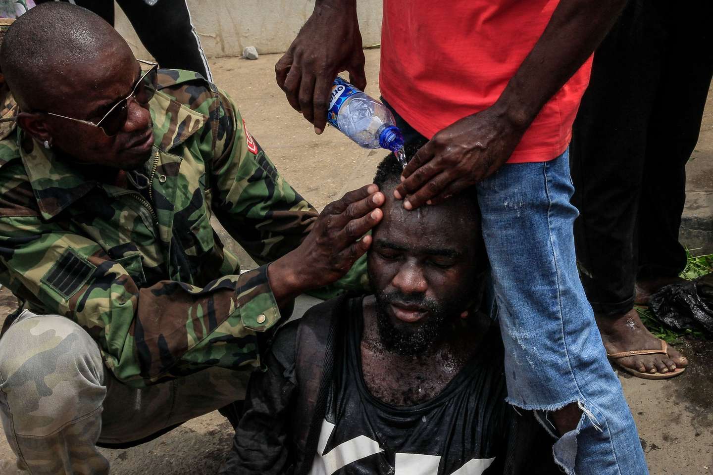 People help an injured man after the police used tear gas to disperse a riot in the surroundings of the city's Santa Ana cemetery, where the kuduro musician known as 'Nagrelha' was to be buried, near Luanda, Angola, 22 November 2022. Gelson Caio Manuel Mendes, better known as 'Nagrelha', the most famous singer in the kuduro musical style, died in Luanda, of lung cancer, according to the Complexo Hospitalar de Doenças Cardiovasculares Dom Alexandre do Nascimento, where he was being cared for. He was 36. AMPE ROGERIO/LUSA
