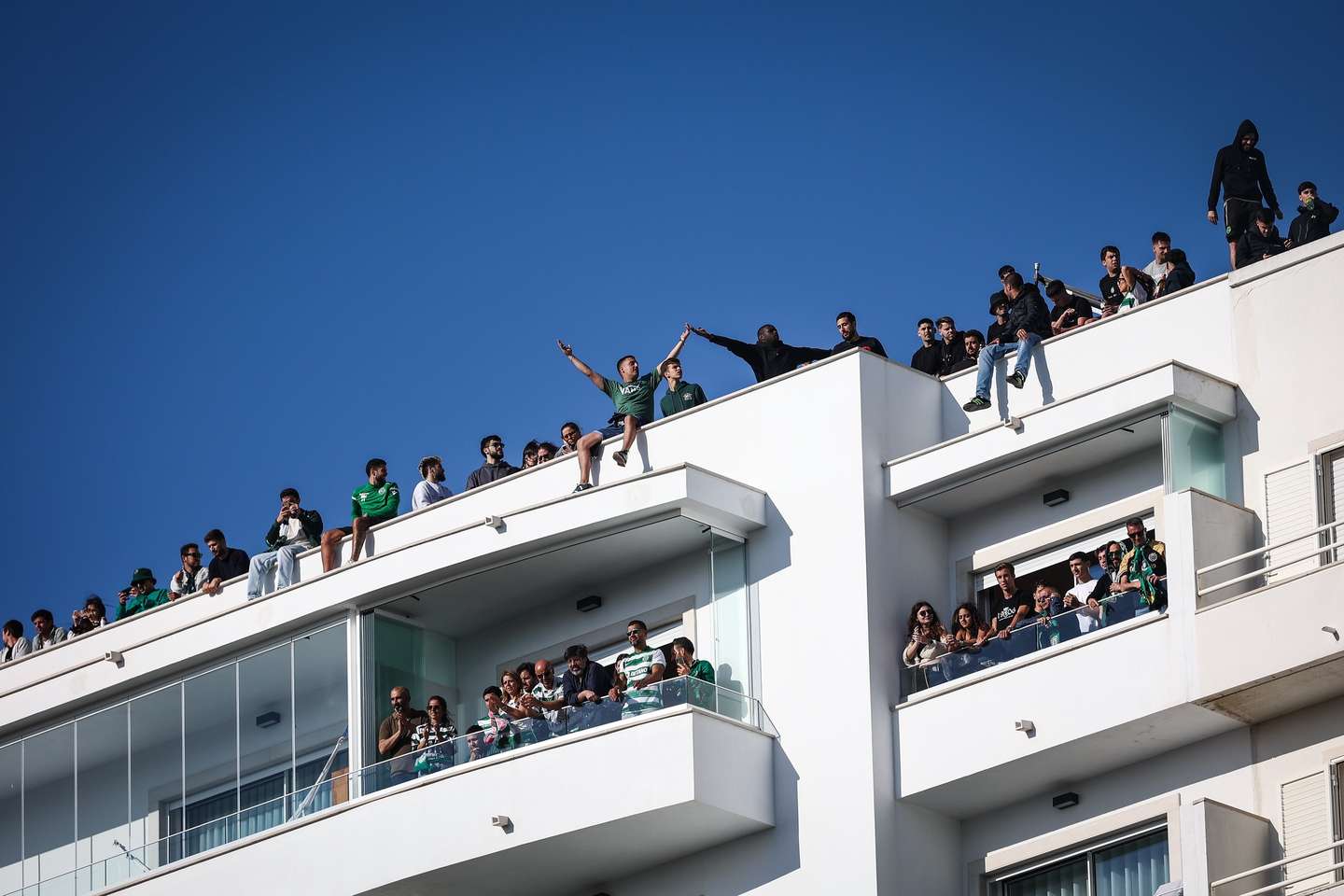 epa11333621 Supporters of Sporting sit in balconies and top of nearby building to cheer during the First League Soccer match between Estoril Praia and Sporting CP, in Cascais, Portugal, 11 May 2024.  EPA/RODRIGO ANTUNES