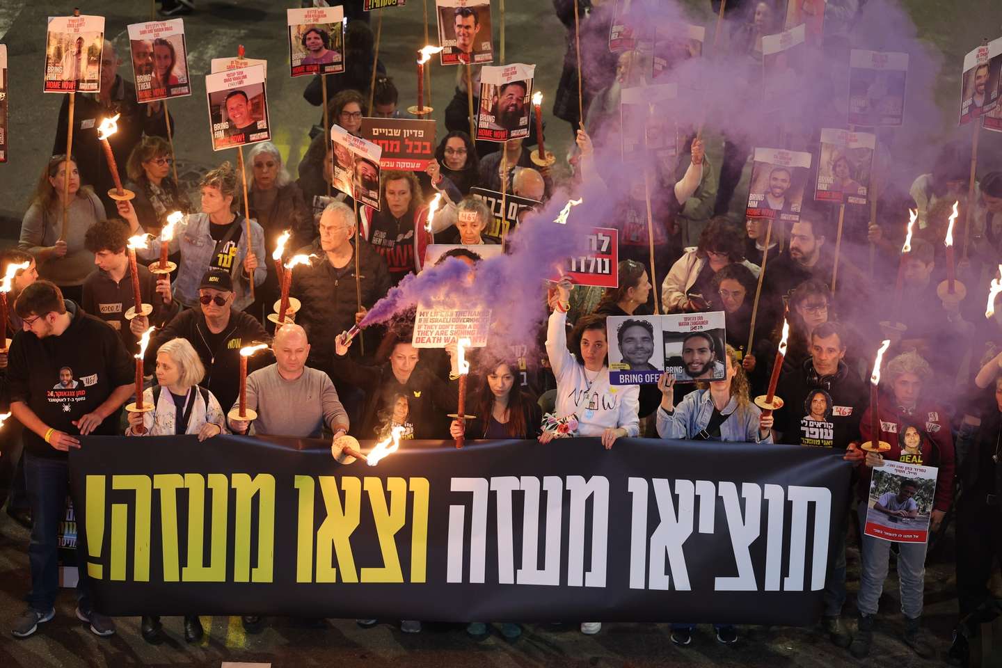 epa11826740 Family members of hostages held by Hamas in Gaza and their supporters light torches as they react to ceasefire reports during a protest calling for a ceasefire and for the release of the hostages, outside the Likud party headquarters in Tel Aviv, Israel, 15 January 2025. According to US and Hamas officials, Israel and Hamas agreed on a hostage deal and ceasefire. The banner reads 'get them out of Gaza and get out of Gaza.'  EPA/ABIR SULTAN