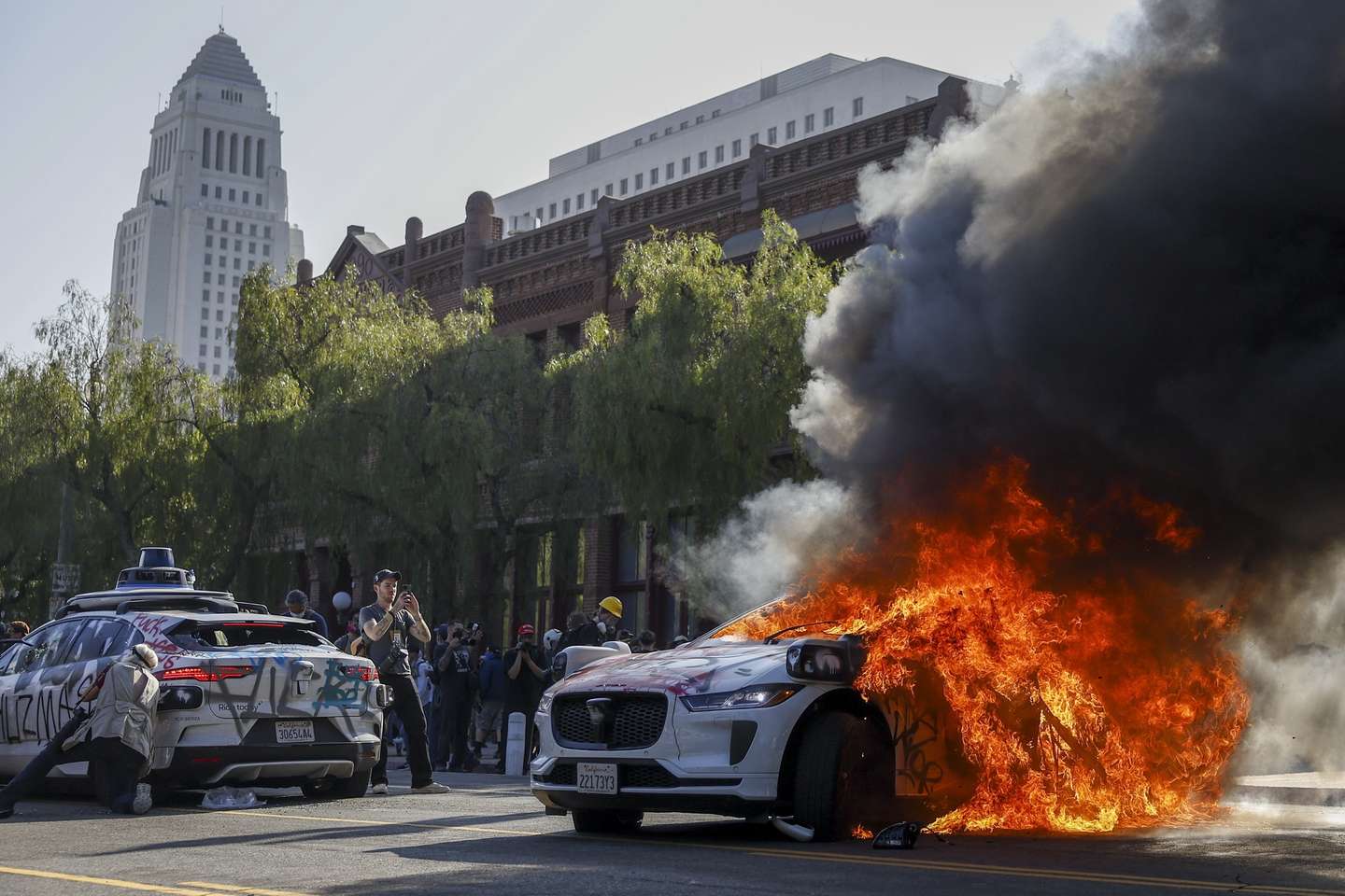 epa12165546 A Waymo self driving car burns as activists protest immigration raids in Los Angeles, California, USA, 08 June 2025. US President Donald Trump has deployed 2,000 National Guard troops, despite not receiving a request from the state of California for any additional assistance, following large protests against ongoing immigration enforcement raids in the Los Angeles area over the last couple of days.  EPA/CAROLINE BREHMAN