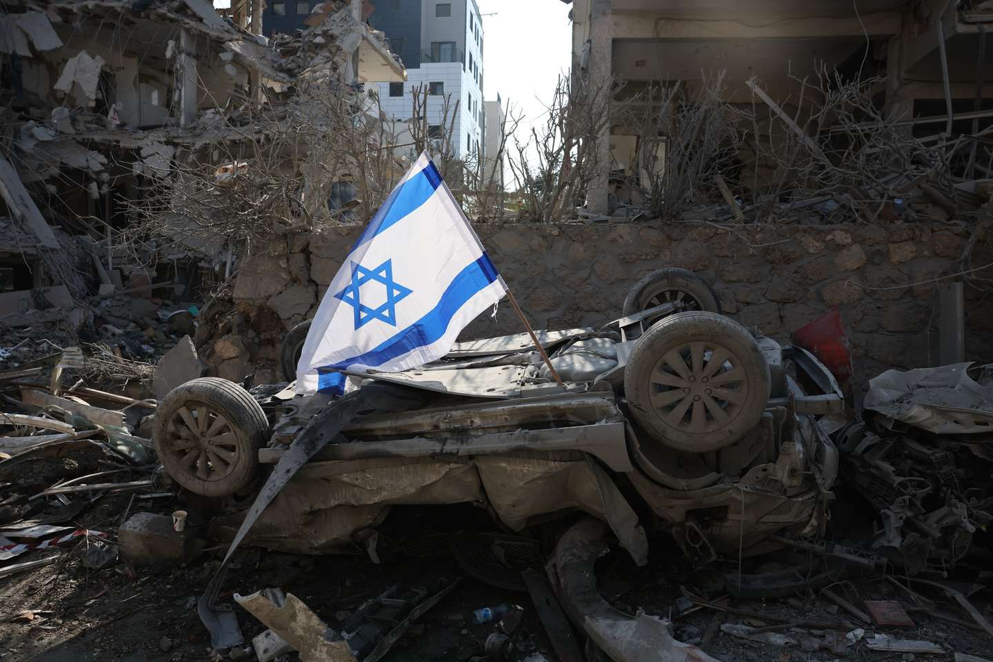 epaselect epa12174587 An Israeli flag placed over a damaged car after a ballistic missile strike in a residential area in Ramat Gan, near Tel Aviv, Israel, 14 June 2025. Israel's military said Iran launched dozens of missiles and drones toward Israel, with some intercepted. Magen David Adom (MDA), Israel's national emergency services, reported at least three killed and dozens of injured, including some in critical condition, in the retaliatory attacks. Israel launched strikes on Iran's nuclear and military facilities on 13 June, targeting top generals and scientists.  EPA/ABIR SULTAN