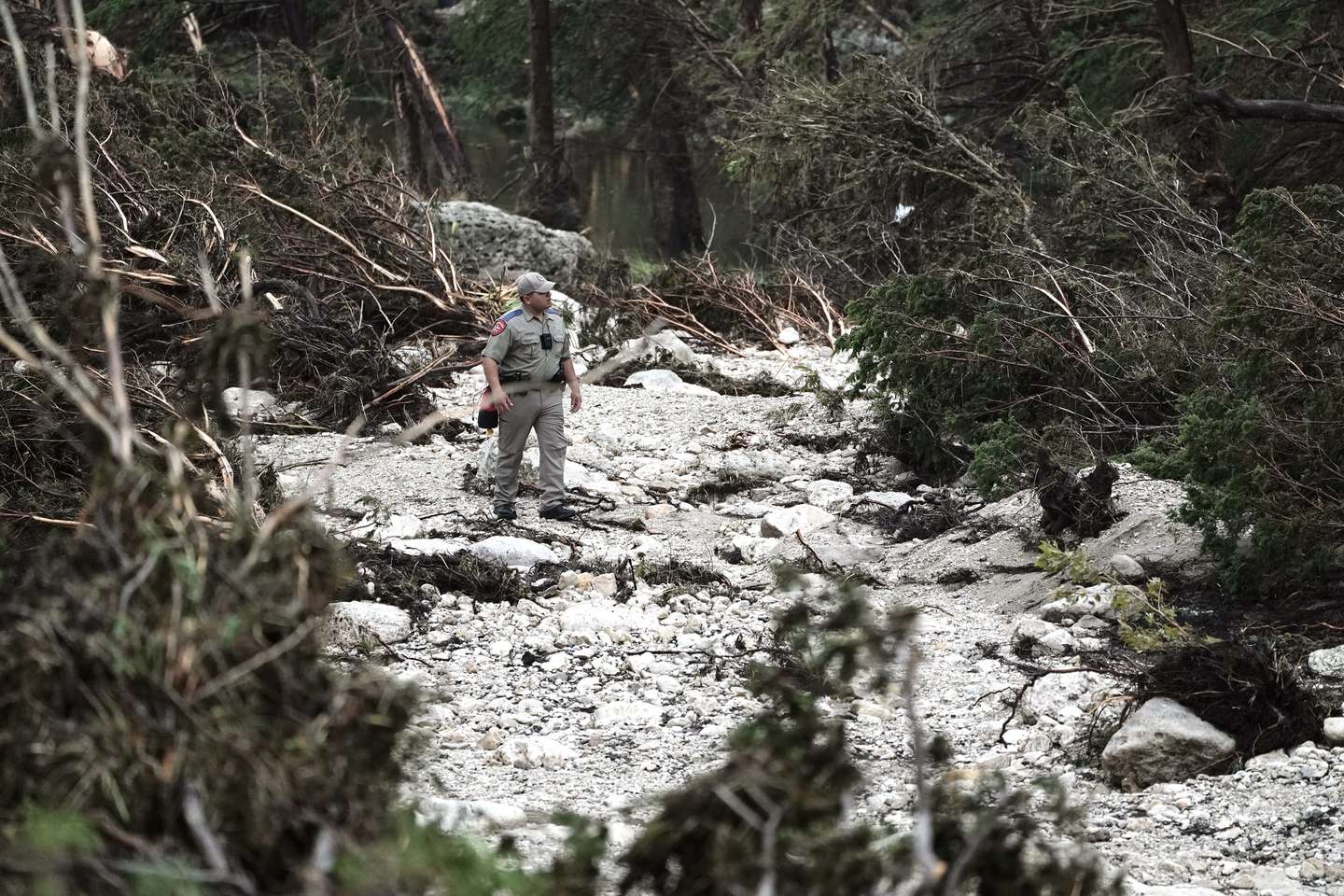 epa12221488 A Texas State Trooper searches a flood zone, in Hunt, Texas, USA, 06 July 2025. At least 69 people have been killed after floodwaters swept through a summer camp and nearby homes on early 04 July.  EPA/DUSTIN SAFRANEK