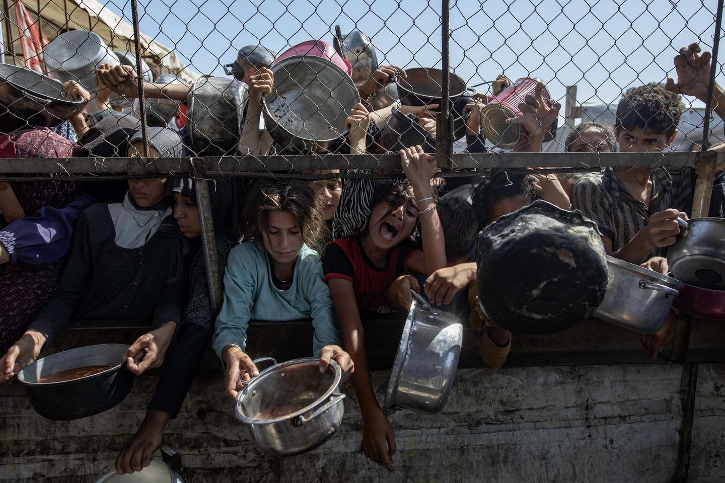 epa12144614 Internally displaced Palestinians gather outside a charity kitchen to receive limited rations amid a shortage of food, in Khan Younis, southern Gaza Strip, 30 May 2025. The United Nations has warned that "the entire population of Gaza is facing the risk of famine" since Israel closed border crossings on 02 March 2025, preventing the entry of essential supplies. The Gaza Government Media Office reported on 24 May that at least 58 people died due to malnutrition, and nearly 250 others due to a lack of food and medicine.  EPA/HAITHAM IMAD