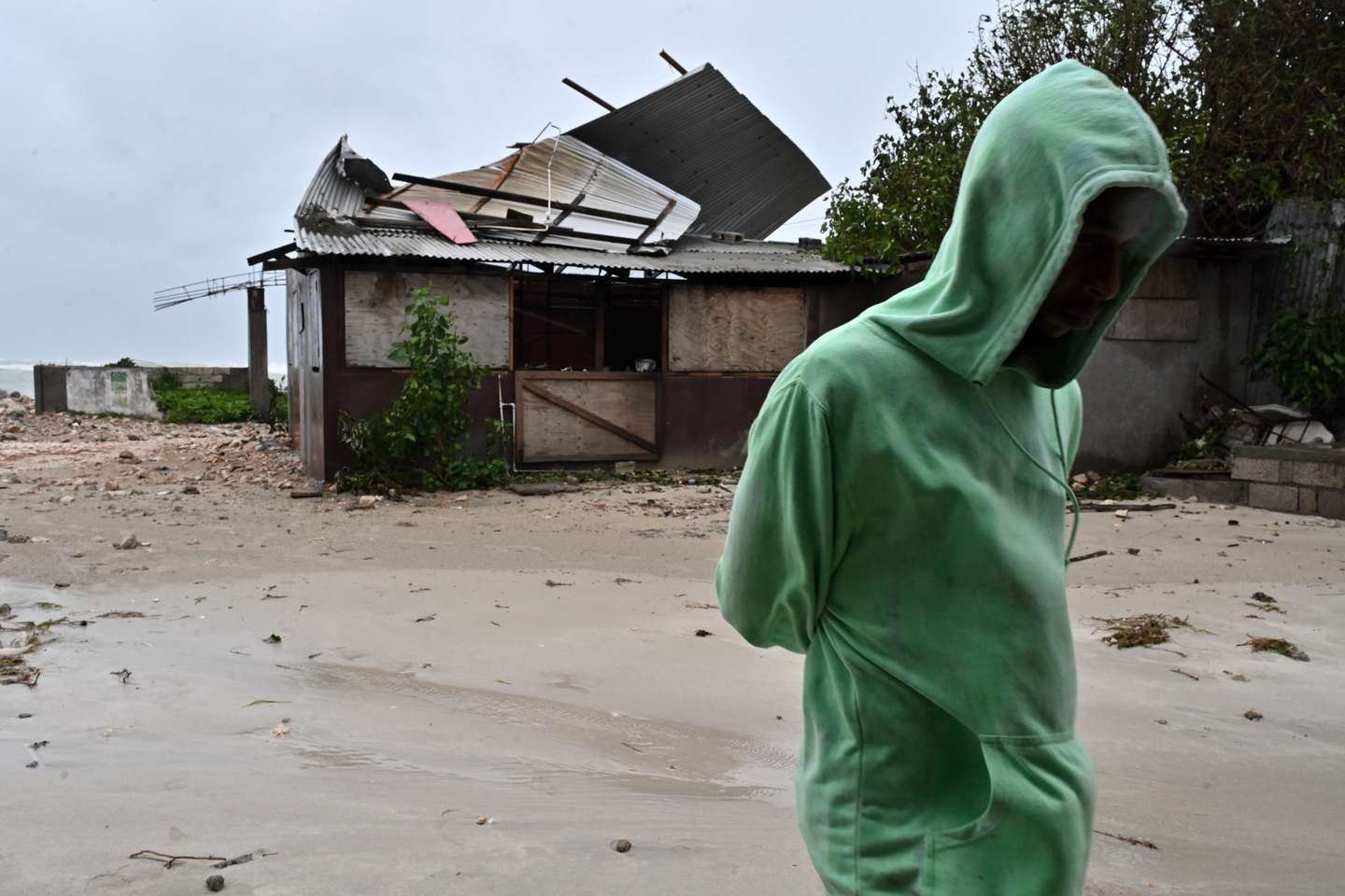 epa12486754 A man walks by a house damaged by the preliminary winds of Hurricane Melissa at Hellshire Fishing Beach in Portmore, Jamaica, 27 October 2025. Jamaican Prime Minister Andrew Holness said the government has a multifaceted plan to ensure a 'swift and effective' response to the storm’s imminent impact on Monday night and forecast to be the island’s strongest recorded storm.  EPA/RUDOLPH BROWN