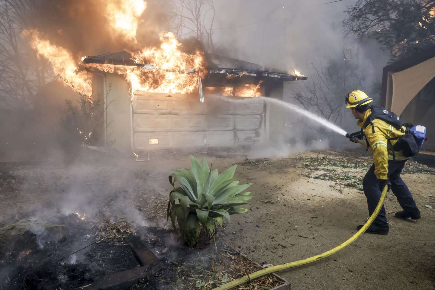 epa11813560 A Los Angeles County firefighter tries to put out a fire from a burning structure during the Eaton wildfire in Altadena, California, USA, 08 January 2025. According to data from California Department of Forestry and Fire Protection, CAL FIRE, multiple wildfires are burning across thousands of acres and forced tens of thousands of evacuations in the Los Angeles area.  EPA/CAROLINE BREHMAN