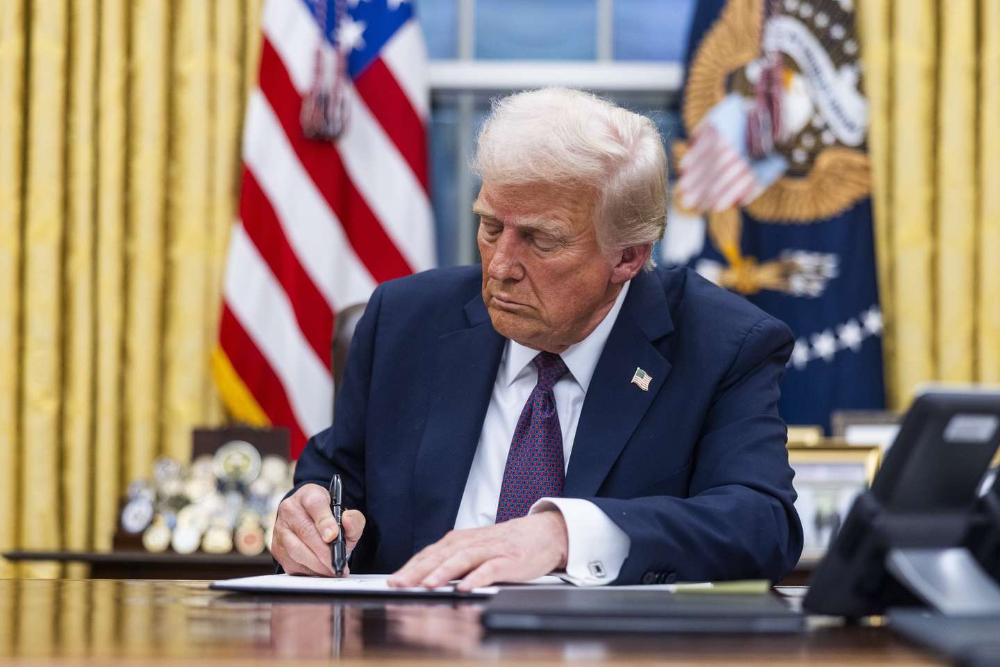 epa11840838 US President Donald Trump signs numerous executive orders, including pardons for defendants from the January 6th riots and a delay on the TikTok ban, on the first day of his presidency in the Oval Office of the White House in Washington, DC, USA, 20 January 2025. Trump, who defeated Kamala Harris to become the 47th president of the United States, was sworn in earlier in the day, though the planned outdoor ceremonies and events were cancelled due to extremely cold temperatures.  EPA/JIM LO SCALZO / POOL