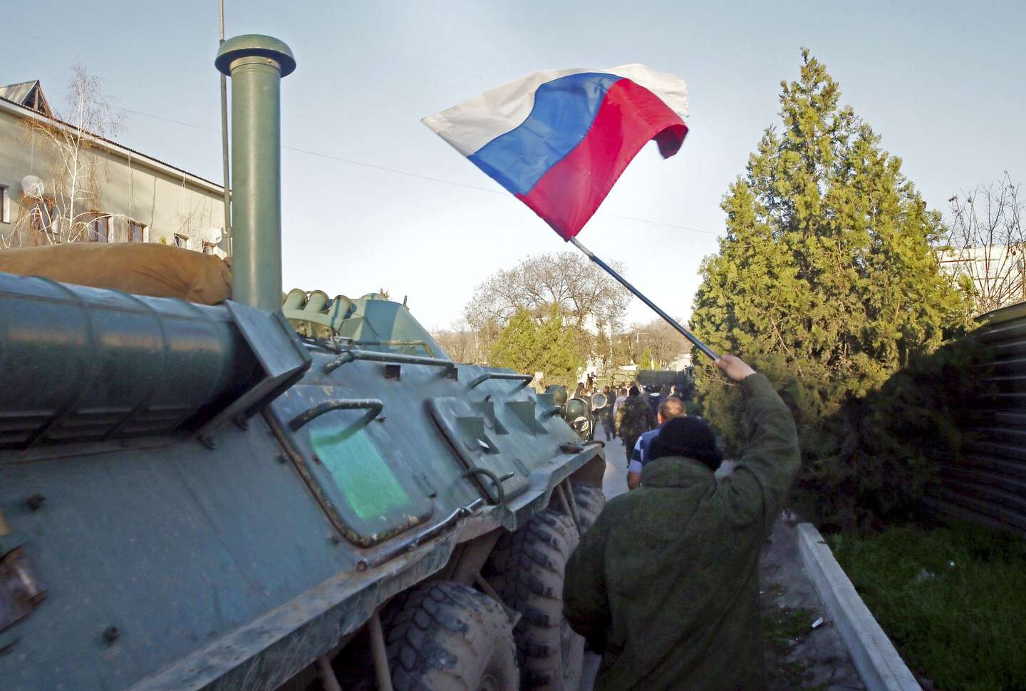 epa04136507 A Crimea's self-defense units member carries a Russian National flag during an assault on the last Ukrainian military base, which has not surrendered after the annexation of Crimea by Russia in Belbek, Crimea, Ukraine, 22 March 2014. Crimean Premier Sergey Aksenov stressed that the base had been liberated from 'foreign troops'. In recent days, Russia has sought to clear out the last few pockets of resistance by browbeating dispirited Ukrainian troops into surrender.  EPA/SERGEI ILNITSKY