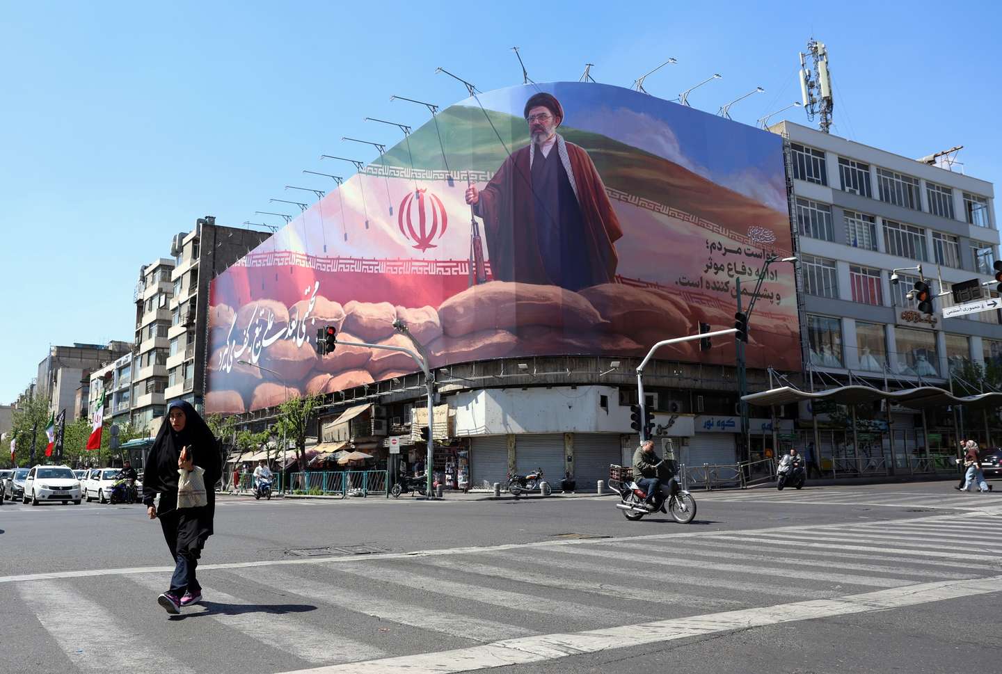 epa12880254 A veiled Iranian woman walk past a large billboard of Iran’s Supreme Leader Ayatollah Mojtaba Khamenei on a street in Tehran, Iran, 10 April 2026. Iran and the US are expected to hold negotiations in Islamabad, Pakistan, following a recently agreed ceasefire.  EPA/ABEDIN TAHERKENAREH