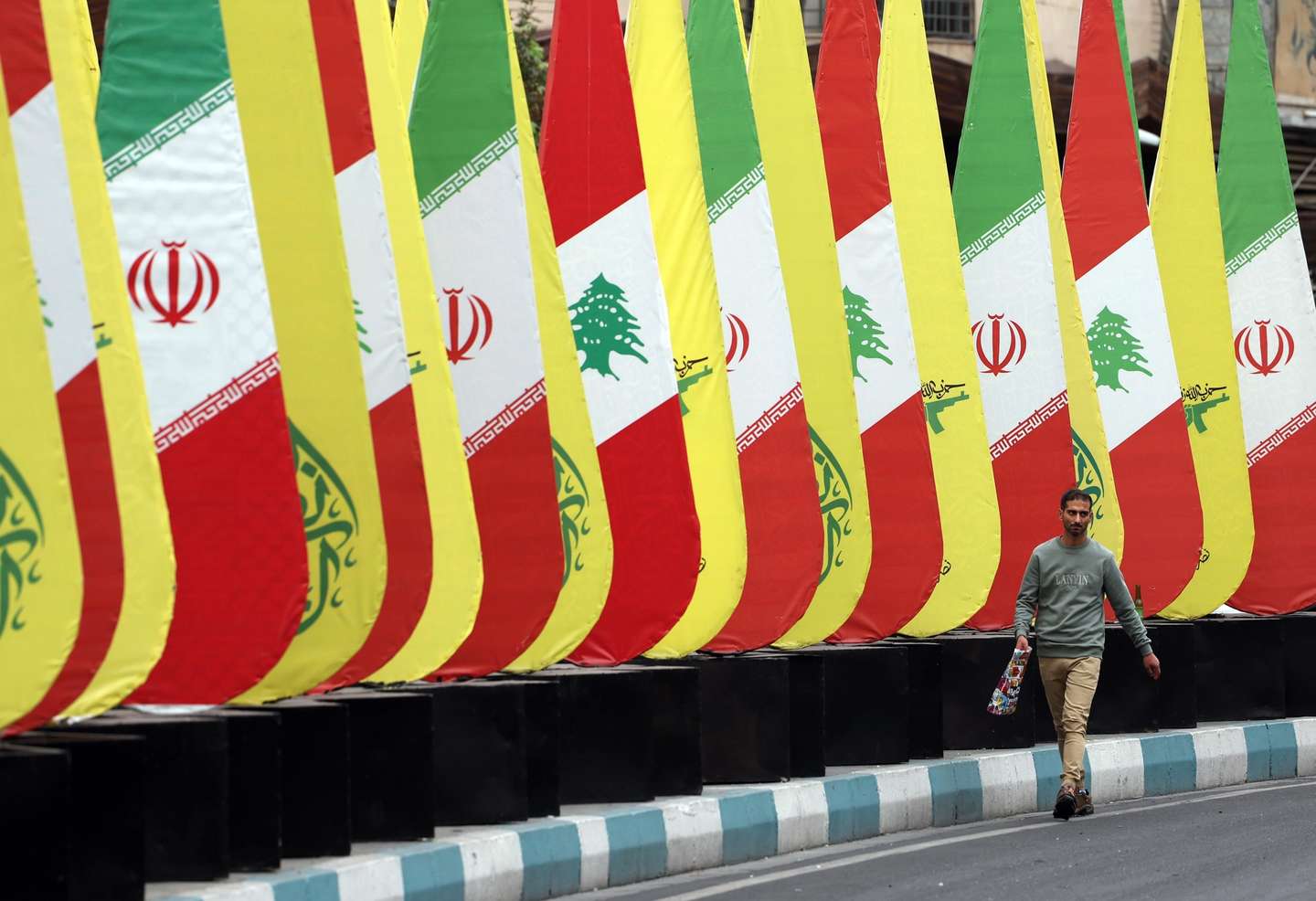 epaselect epa11672953 An Iranian man walks past a decoration of Iranian-Lebanese and Hezbollah flags in a street in Tehran, Iran, 21 October 2024. Iranian supreme leader Ayatollah Ali Khamenei on 19 October issued a message over the death of Yahya Sinwar, stating that 'the resistance did not stop after the death of its leaders, and it will not stop'. The Israeli Army, Tsahal, on 17 October 2024 confirmed that Hamas leader Yahya Sinwar was 'eliminated' on 16 October 'after a year-long pursuit'.  EPA/ABEDIN TAHERKENAREH