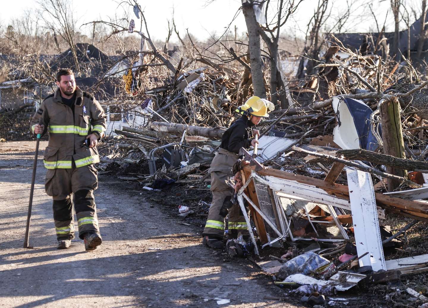 epa09639468 Firefighters clear debris from a street after a tornado left widespread destruction of homes and businesses in Mayfield, Kentucky, USA, 12 December 2021. According to reports more than 70 people lost their lives in Kentucky with more dead in Arkansas in the storms on 10 December.  EPA/TANNEN MAURY