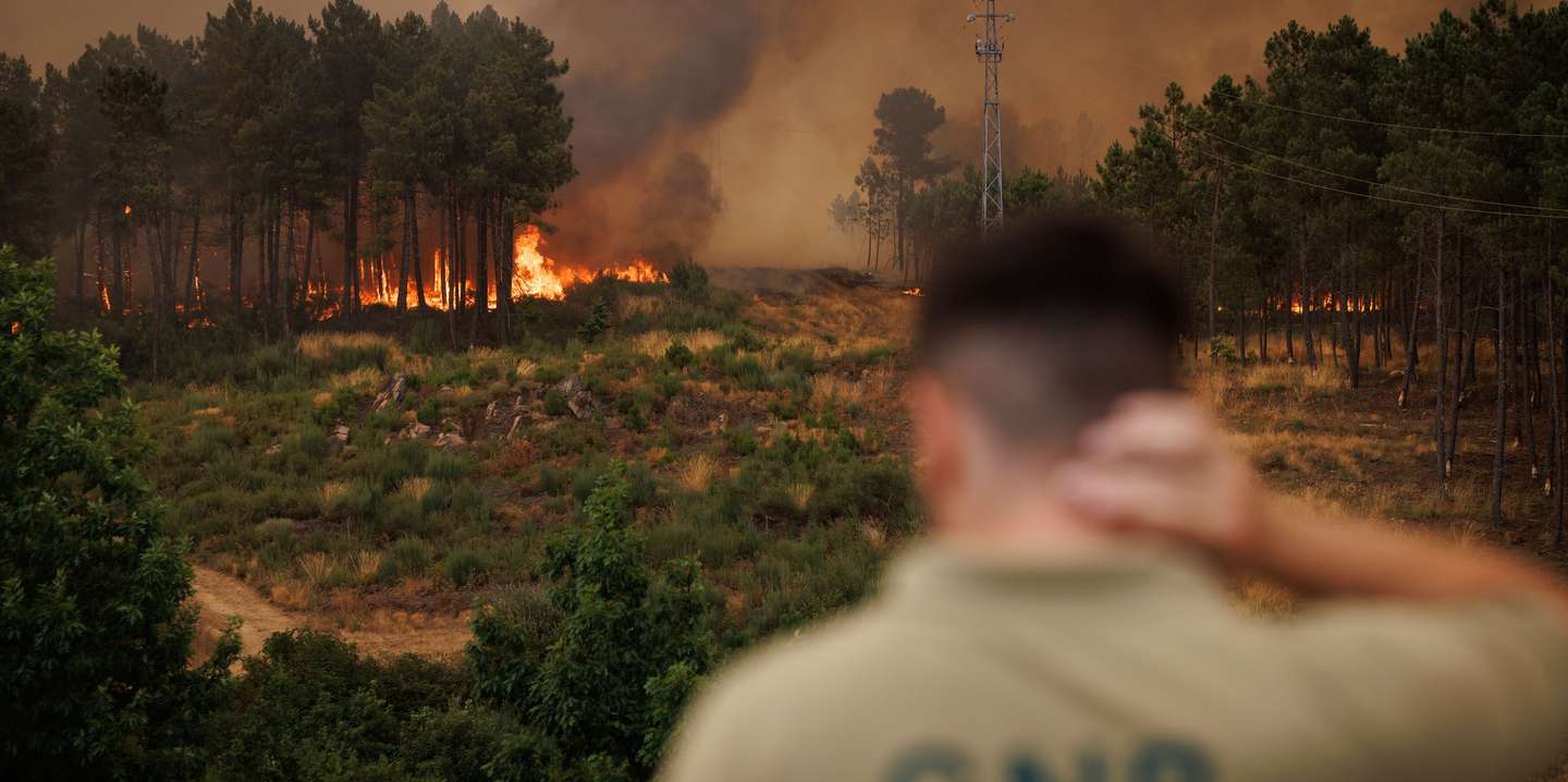 Um agente da GNR observa as chamas durante um incêndio em São Martinho da Anta, concelho de Sabrosa, Vila Real, 2 de agosto de 2025. O fogo que começou em São Cibrão, Vila Real, alastrou para o concelho de Sabrosa, onde lavra em duas frentes com alguma intensidade e mobiliza cerca de 240 operacionais. PEDRO SARMENTO COSTA/LUSA