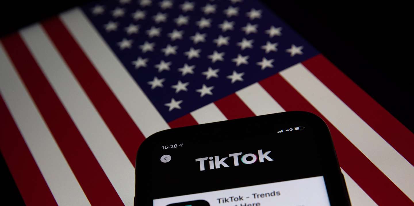 epa08685860 A generic illustration shows the icon of Chinese internet media app TikTok on a phone, and the US flag on a laptop screen, in Beijing, China, 21 September 2020. Chinese-owned mobile app WeChat was set to stop operation in the U.S. on midnight 20 September 2020.  EPA/ROMAN PILIPEY