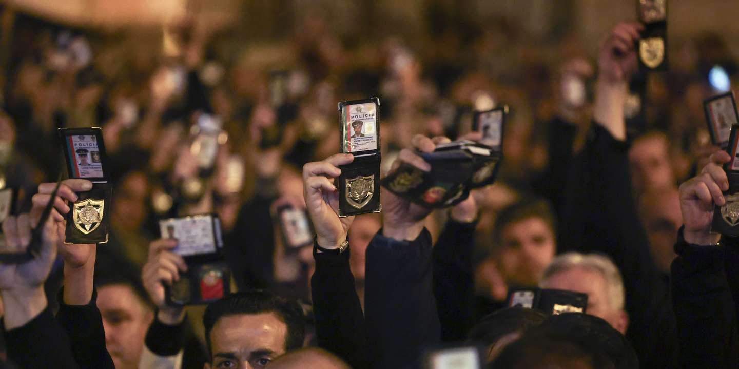 epa11101982 Police officers hold up their badges as PSP (Public Security Police) and GNR (National Republican Guard) police forces march towards the Portuguese Parliament during a demonstration against the government policies regarding a pension given to the Judiciary Police and not to the other police forces, in Lisbon, Portugal, 24 January 2024.  EPA/JOSE SENA GOULAO
