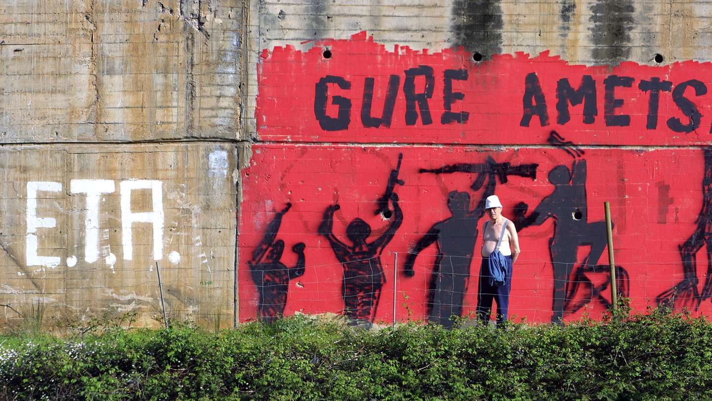A man stands in front of a mural paintin