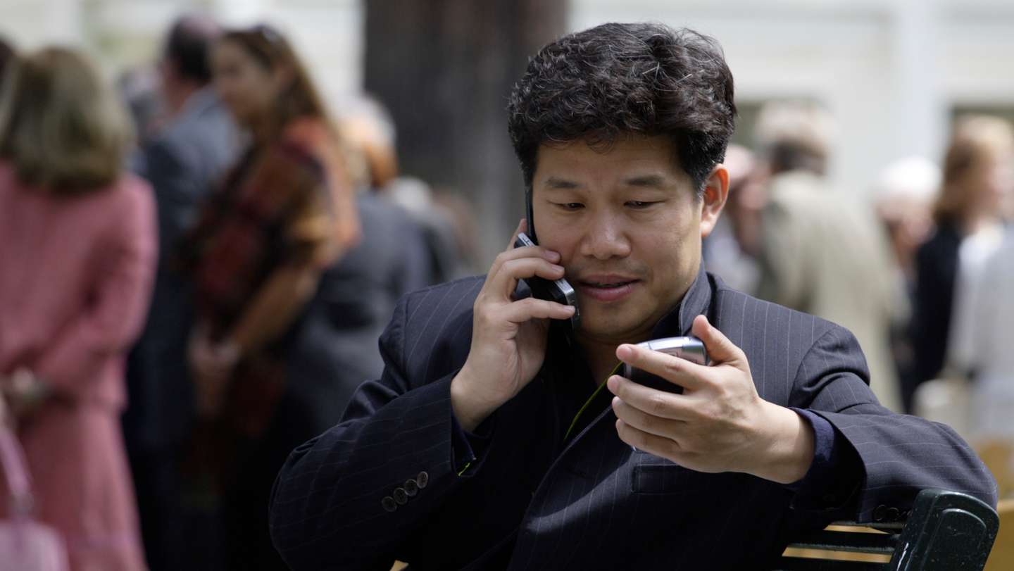 Donald Tang talks on a cellphone and reads a Blackberry at a USC event, May 2, 2007. Tang is the ch