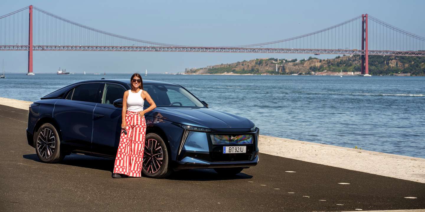 Bárbara Tomaz posa ao lado do automóvel DS com a ponte 25 de abril ao fundo.