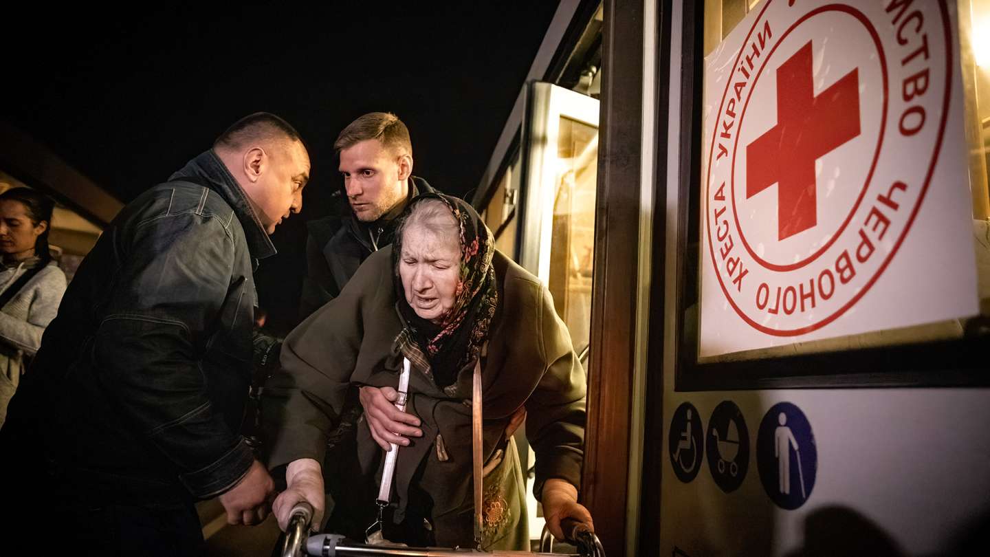 Volunteers assist an old lady to get off the bus after she