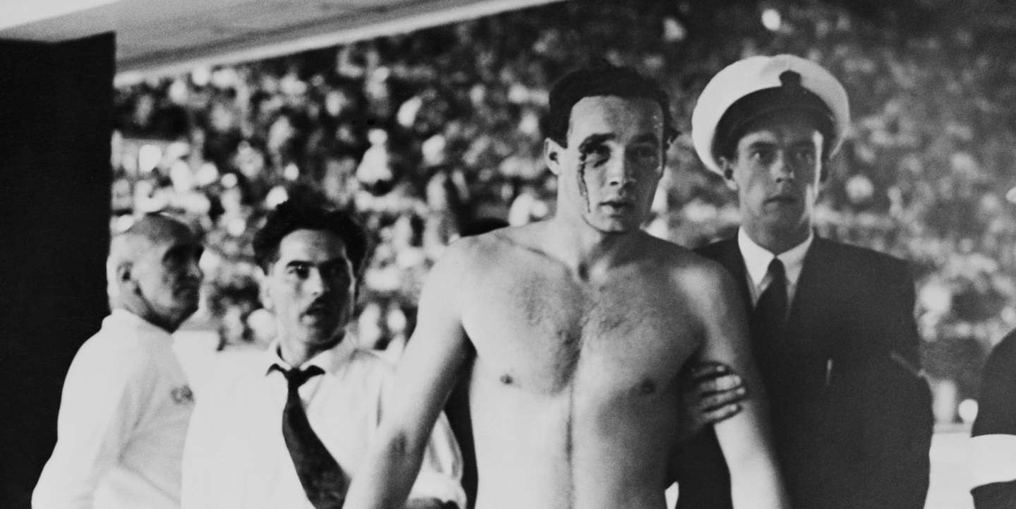 Um nadador de pólo aquático húngaro a ser escoltado depois da agressão de um atleta da URSS (Melbourne, 1956)