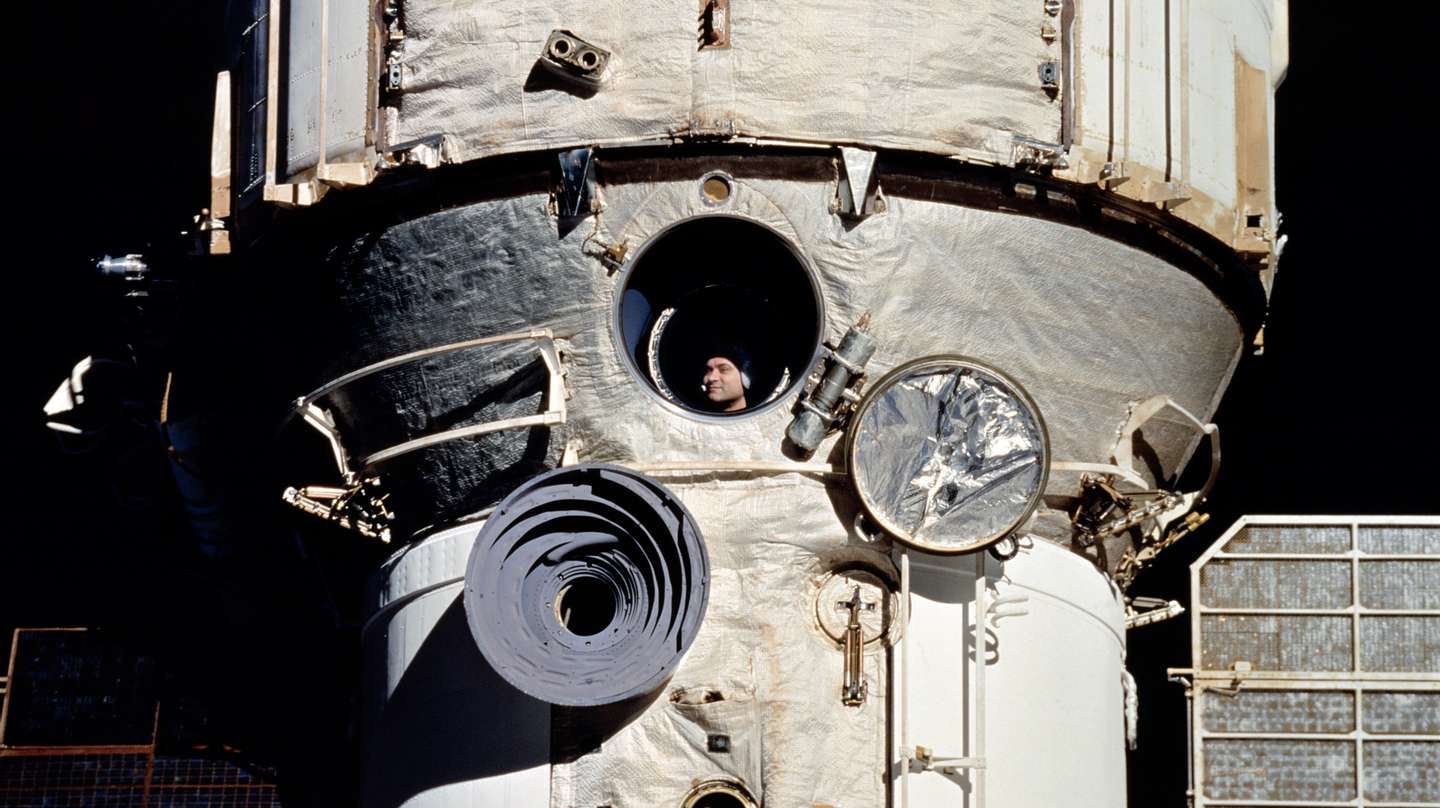 À janela da estação espacial Mir, o cosmonauta Valeri Polyakov aguarda o encontro com a nave espacial norte-americana Discovery