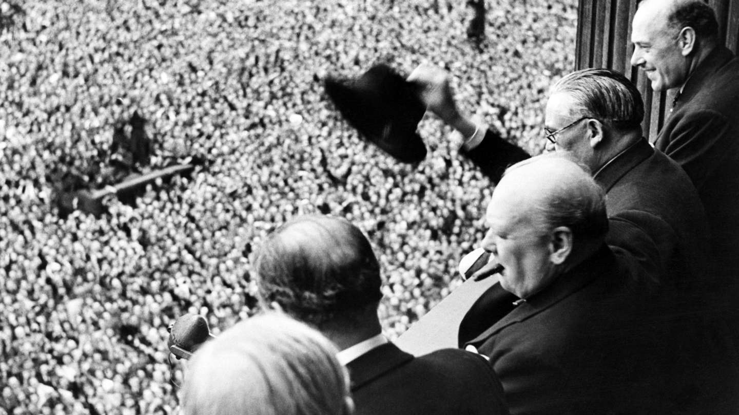 Sir Winston Churchill looking out over crowds celebrating the end of the Second World War in London.