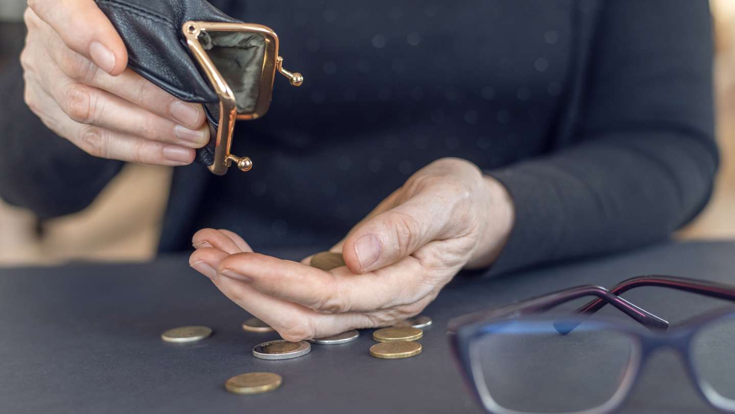 An elderly woman holds an open empty wallet in her hands, the concept of poverty, pension