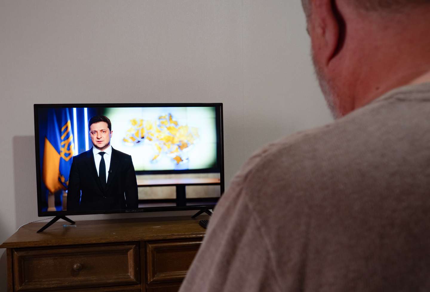 A man watches as President Volodymyr Zelensky delivers a