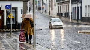 Uma popular protegida por um guarda-chuva passa pela rua do Galo, deserta de pessoas, devido aos efeitos que já estão a ser sentidos, com o aumento gradual do vento e chuva nos grupos central e oriental do arquipélago dos Açores, da passagem do furacão Alex, na Praia da vitória, Ilha Terceira, 15 de janeiro de 2016. Segundo o IPMA  Instituto Português do Mar e da Atmosfera, o período mais crítico ocorrerá entre as 08:00 e as 11:00 de hoje (hora local, menos uma hora do que em Lisboa), quando se prevê a sua passagem em cima do arquipélago. ANTÓNIO ARAÚJO/LUSA